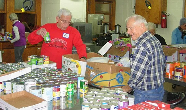 2 MWA volunteers prepare donated food for distribution