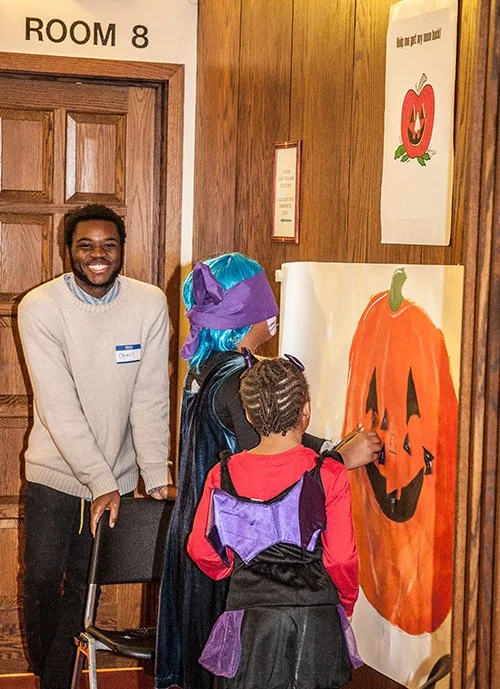 An MWA volunteer leads games with children a Halloween event