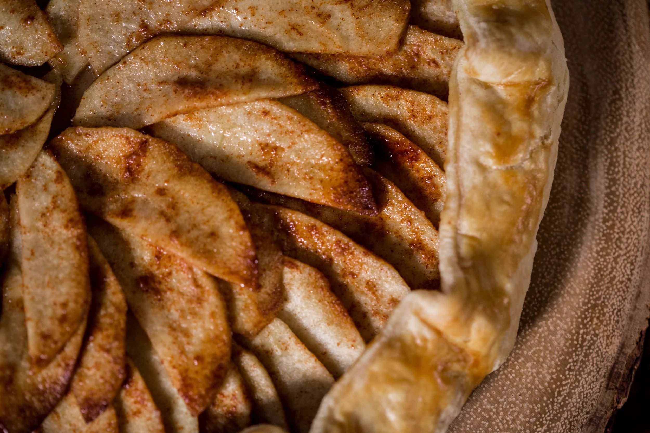 Close up photo of an able pie showing the pie edge and apple slices in a kitchen.