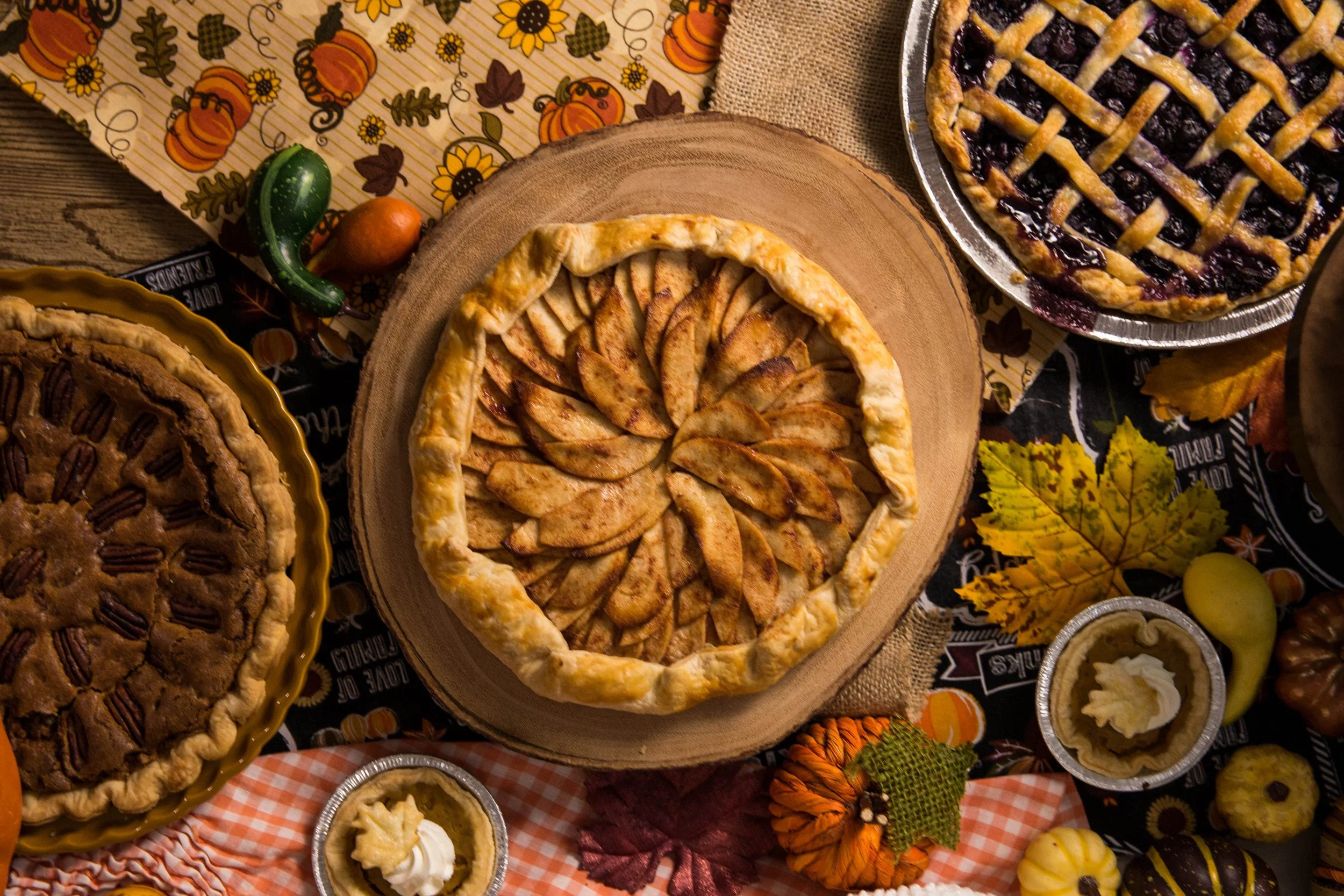 An apple, pecan, and blueberry pie with small pumpkin pies around them at a bakery in Utah County, Utah.