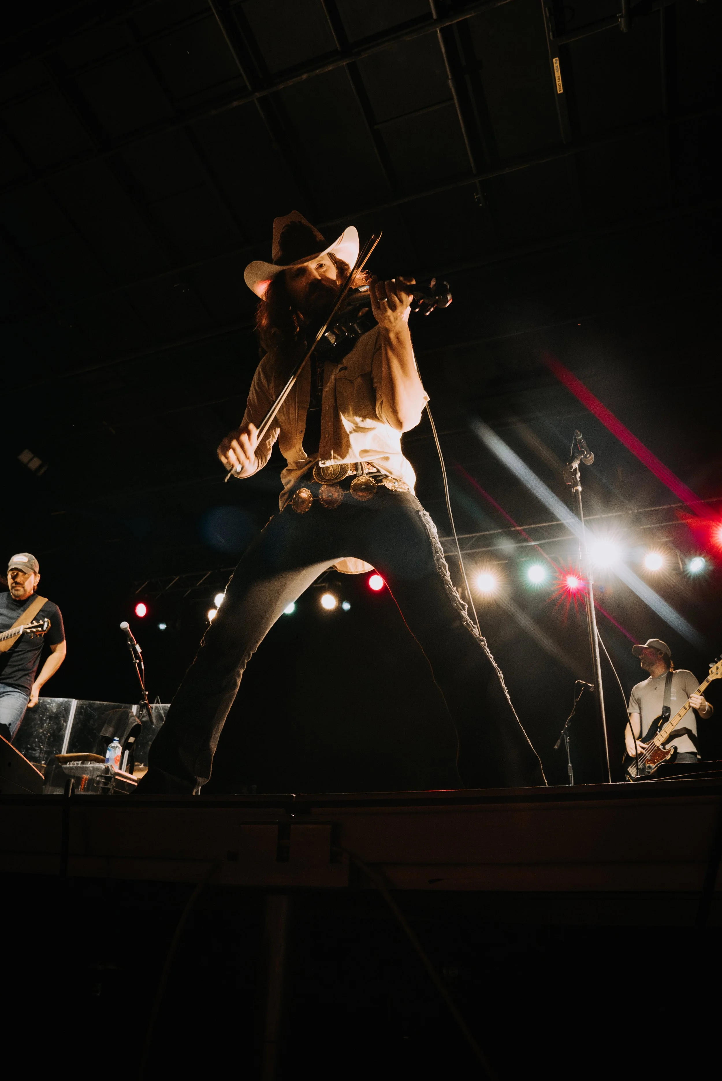 A photo of Rodney Atkins' fiddle player on stage at the Summit County Fairground with stage lights streaking behind him in Coalville, Utah.