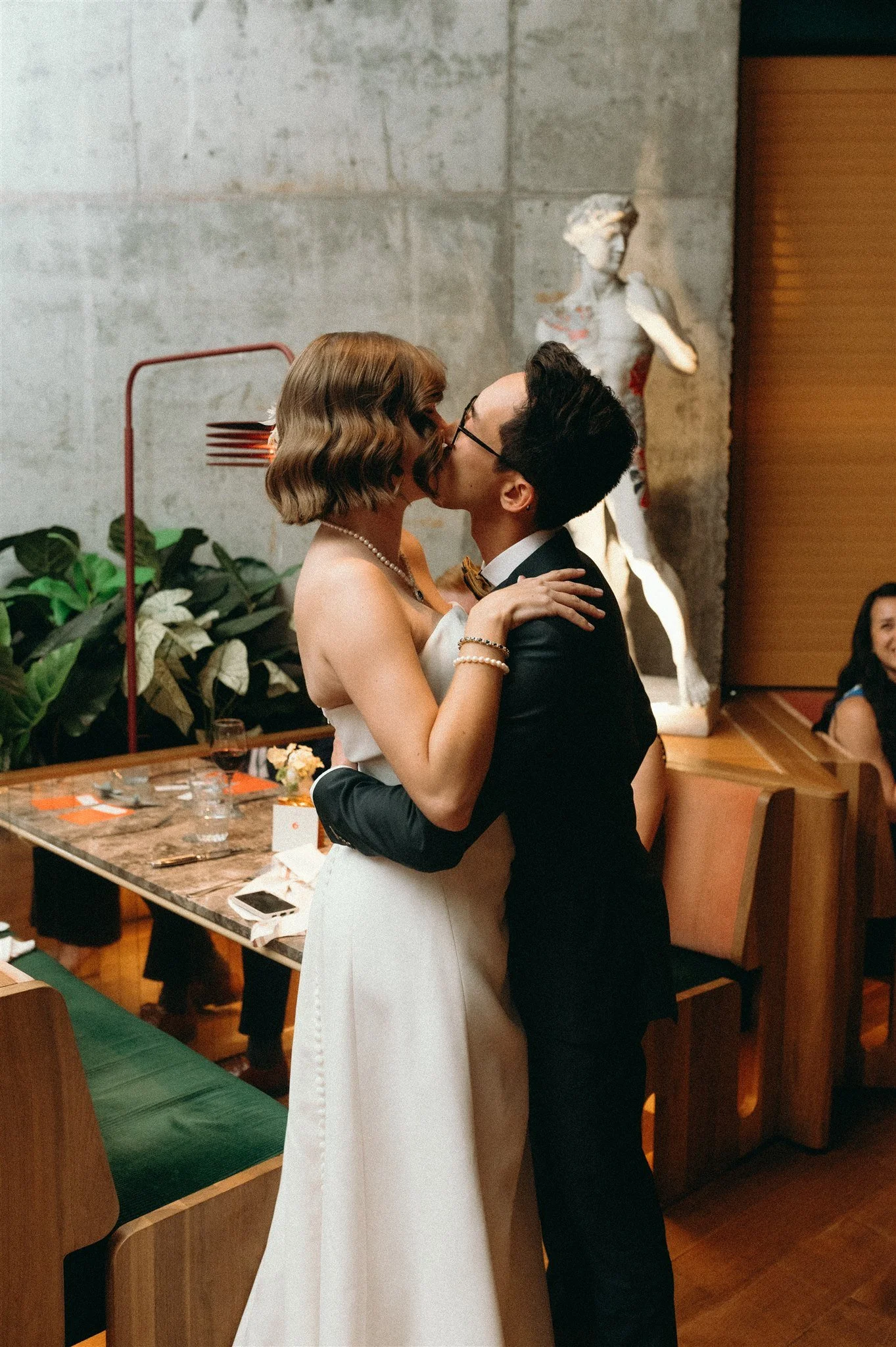 Deux personnes en robe de mariée et costume s'embrassent lors de leur mariage intime au Tiramisu à Montréal