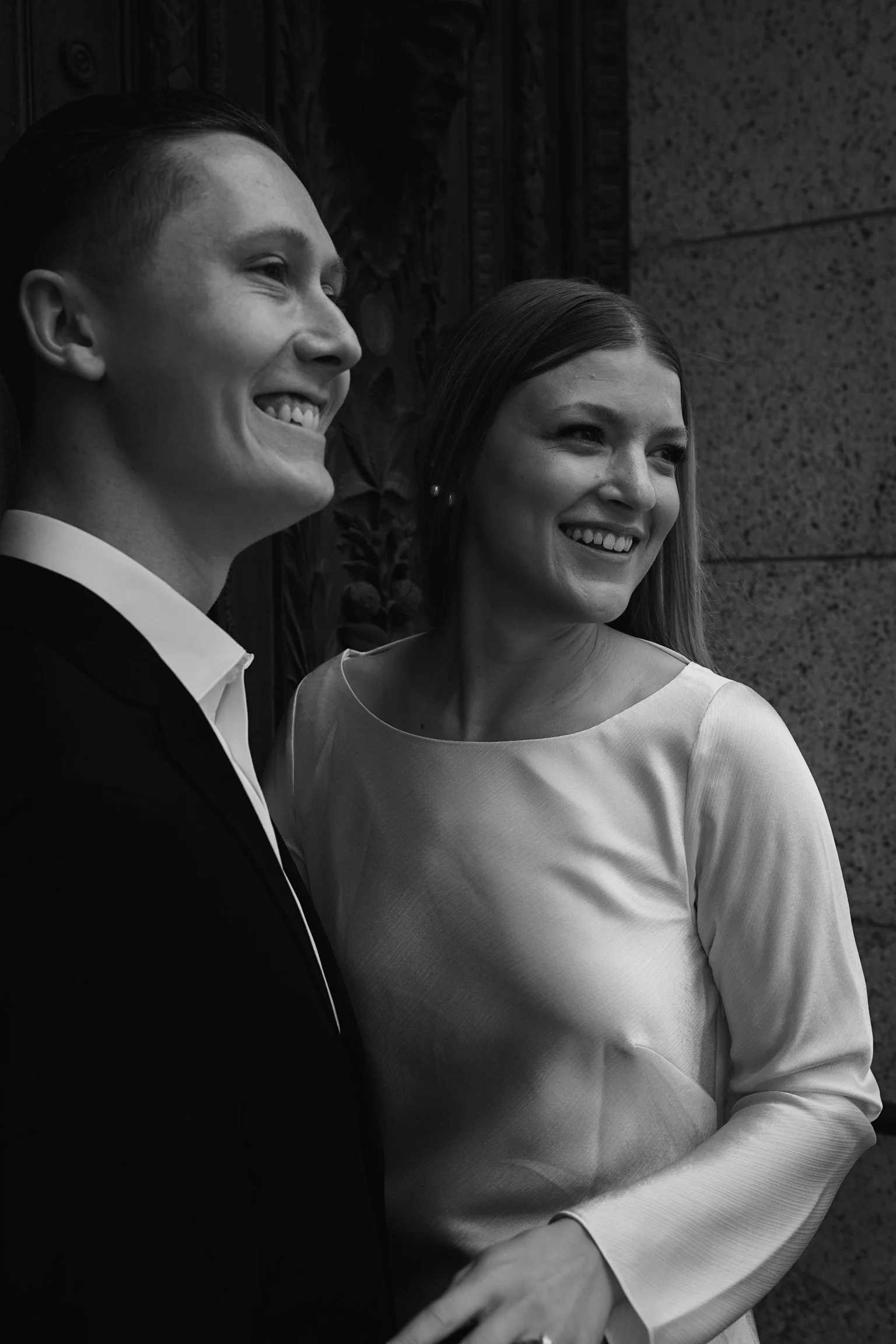 A smiling man and woman dressed in formal attire standing together outdoors.