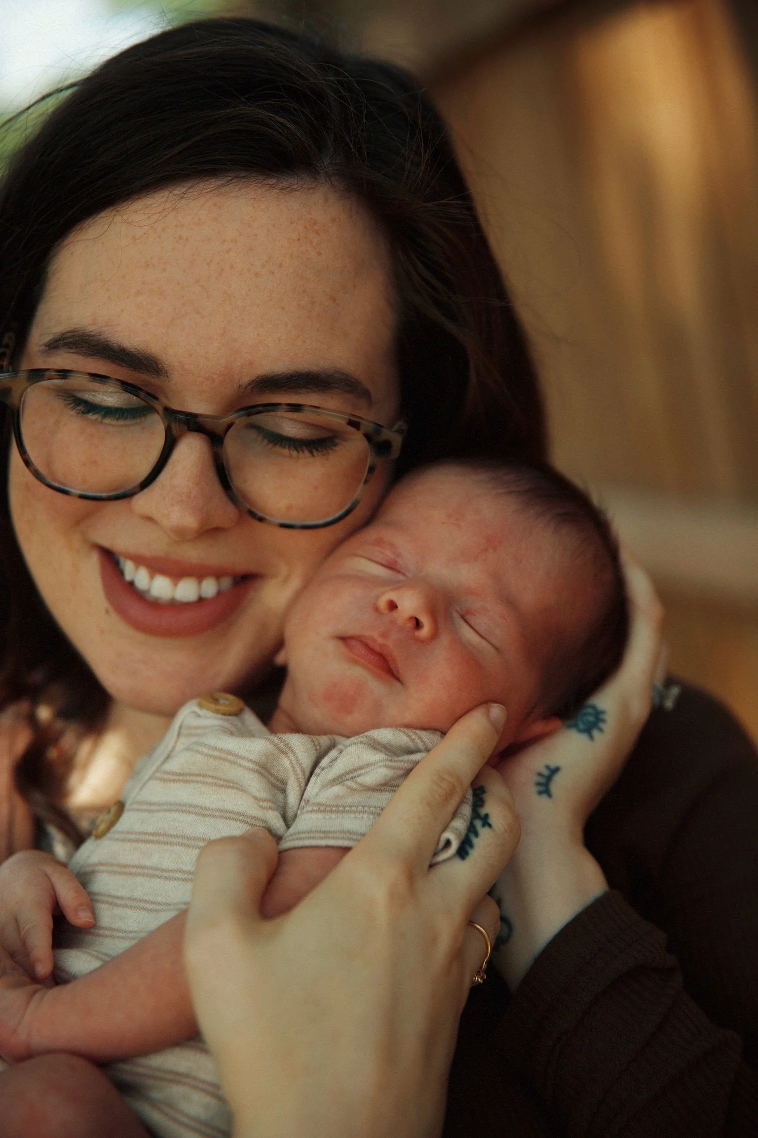 A woman with glasses gently holding a sleeping baby