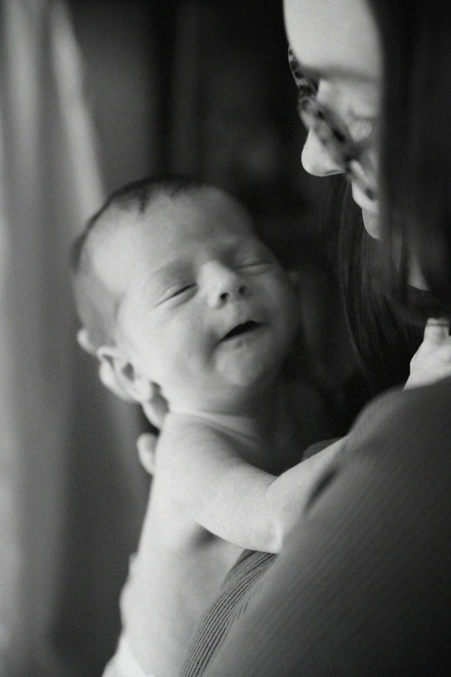 A woman holding a smiling baby close to her face, with both appearing happy and content.