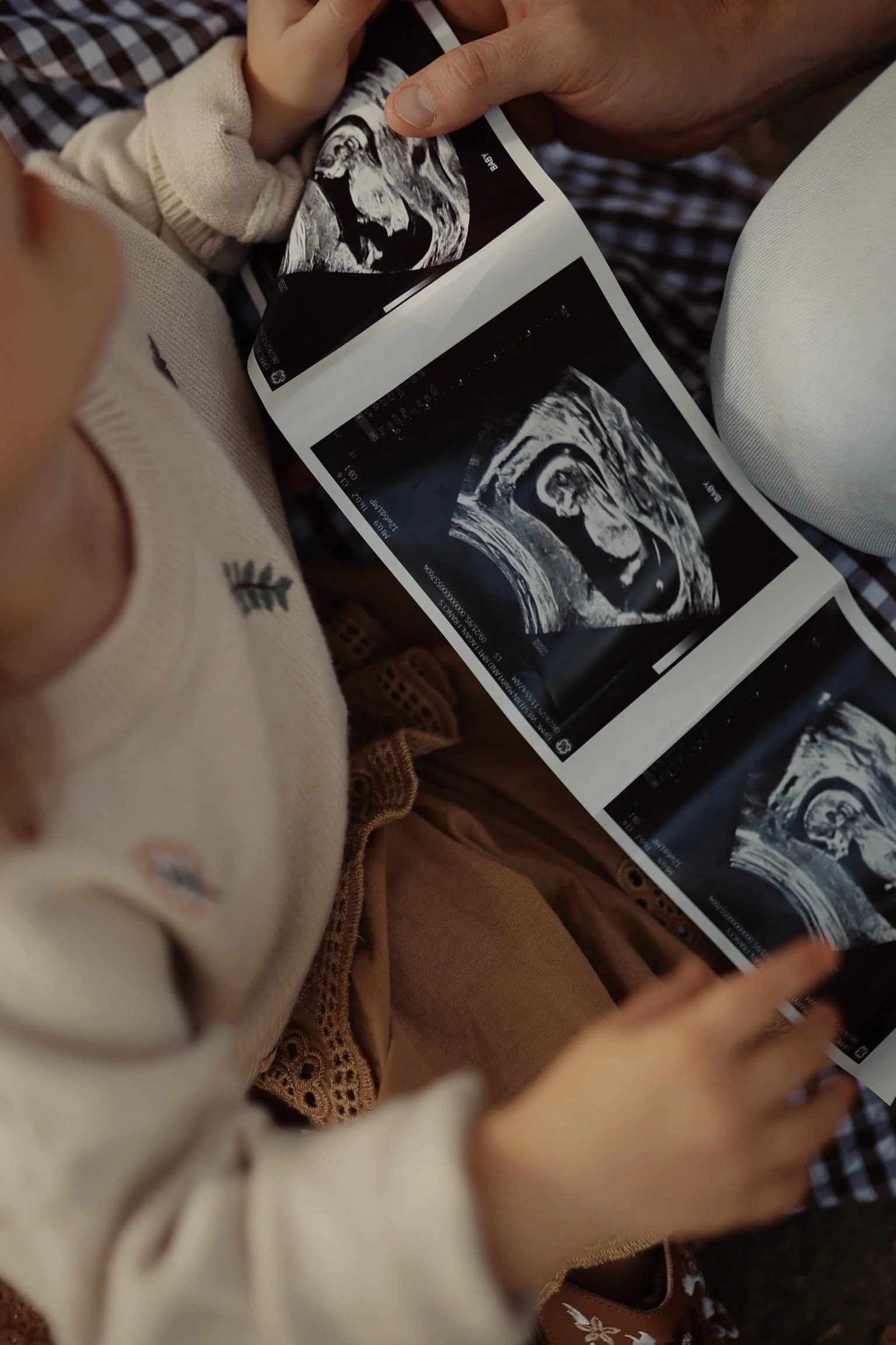 A child and an adult are looking at ultrasound images of a developing fetus.