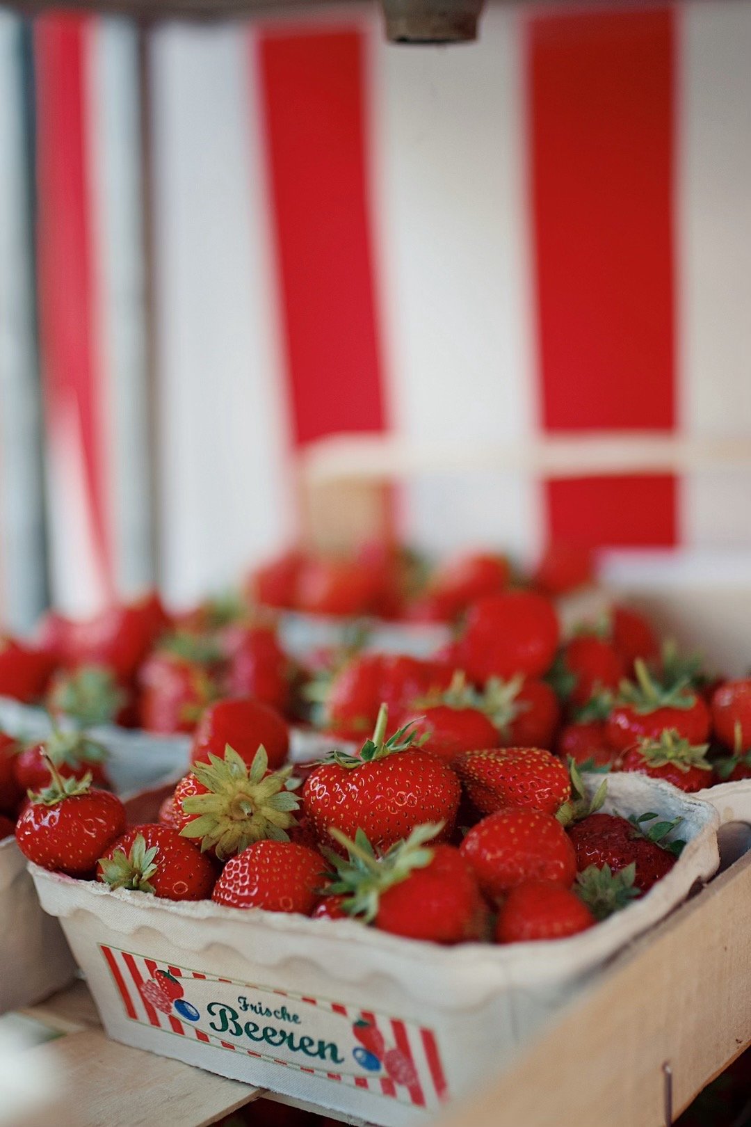 Fresh strawberries in a cardboard container with a red and white striped background.