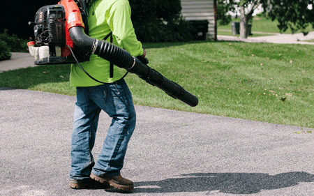 Person using a leaf blower on a driveway