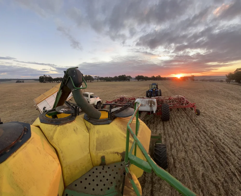 Tractor and farm equipment in a paddock at sunset
