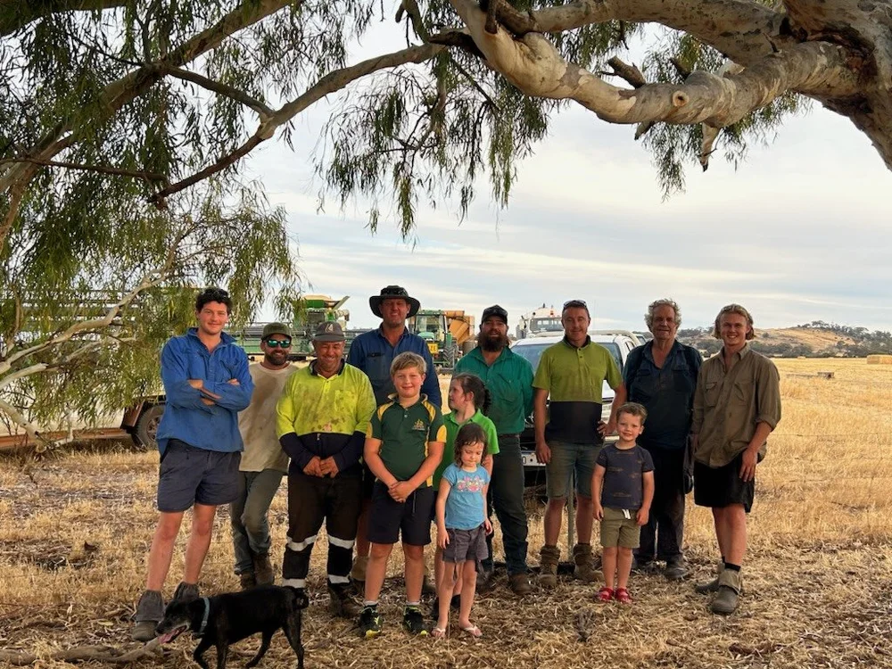 Group of people standing together outdoors near farm equipment