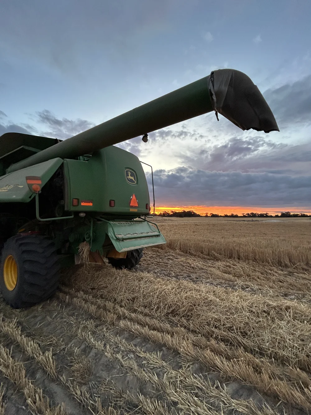 Header in a paddock at sunset