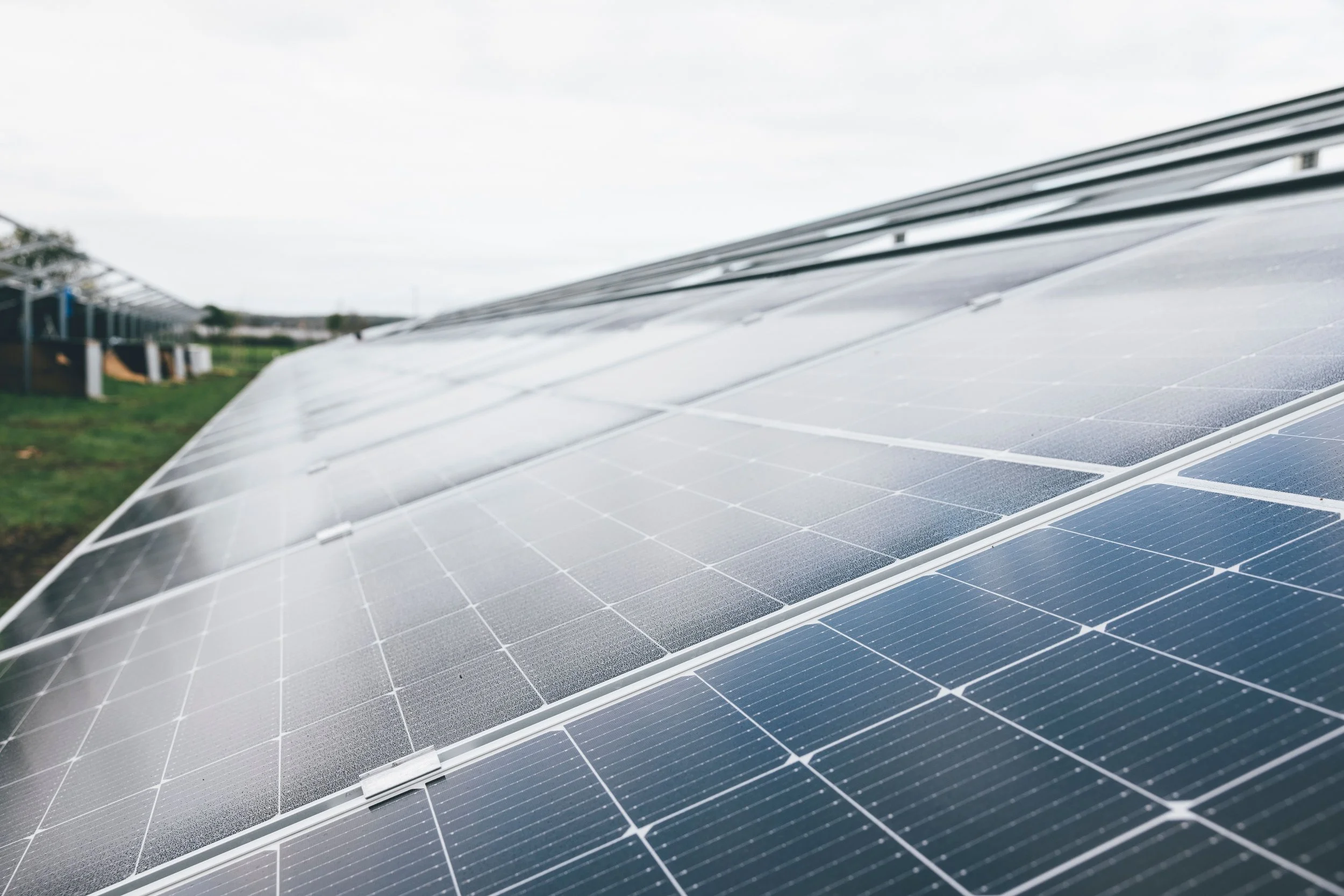 Close-up of solar panels at an outdoor solar farm under a clear blue sky, showcasing modern renewable energy technology.