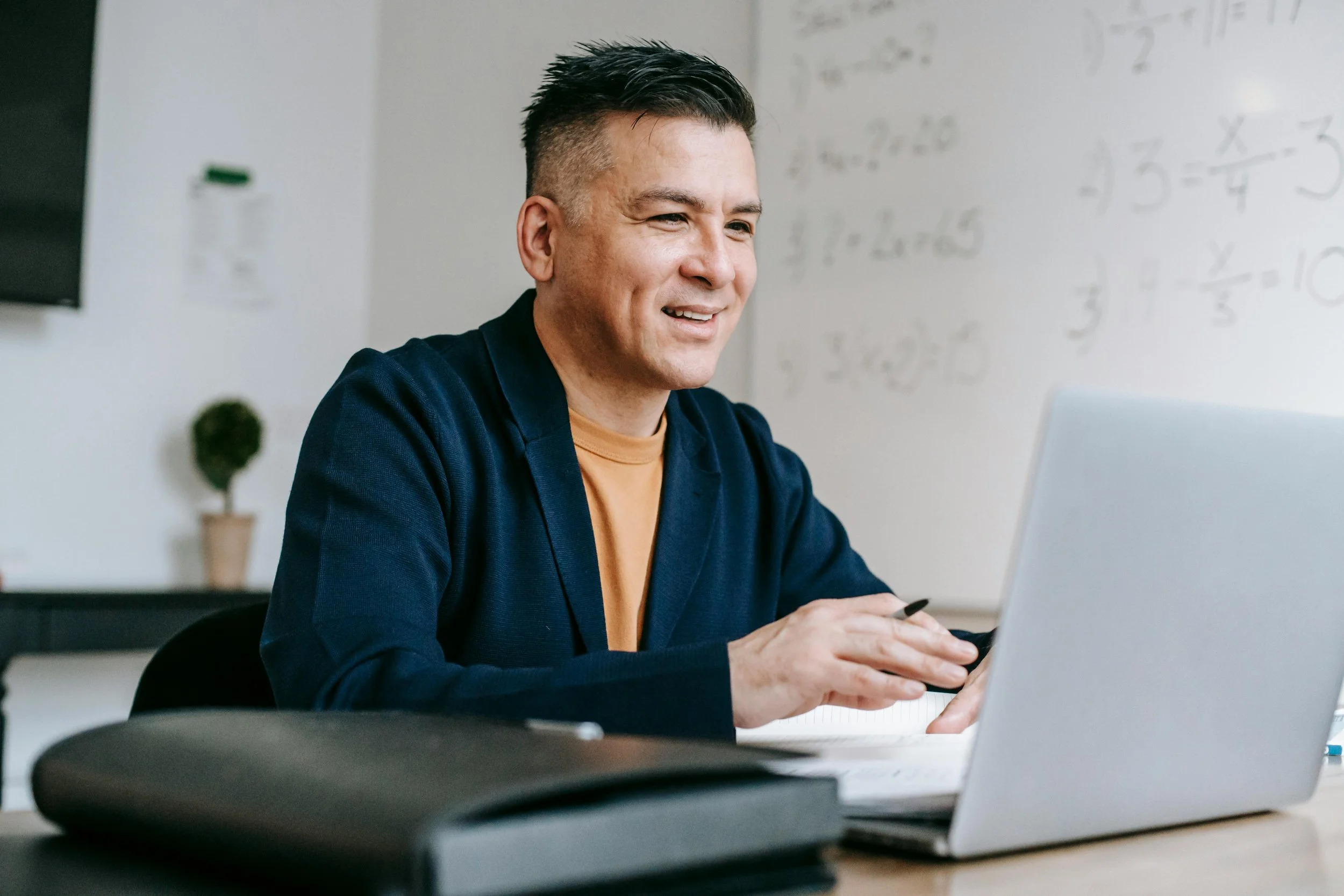 A smiling man working on his laptop, representing focus, productivity, and the power of self-discipline.
