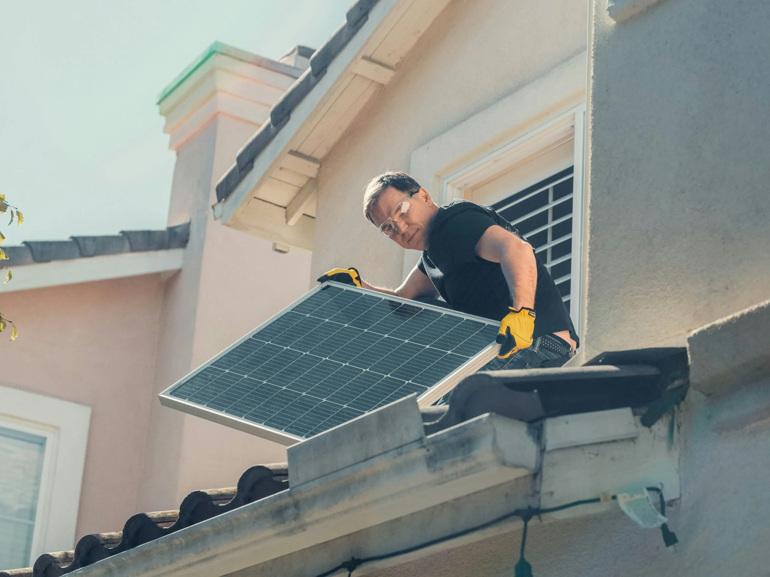 Homeowner installing a solar panel on the roof of their house, illustrating the transition to renewable energy and sustainable living.