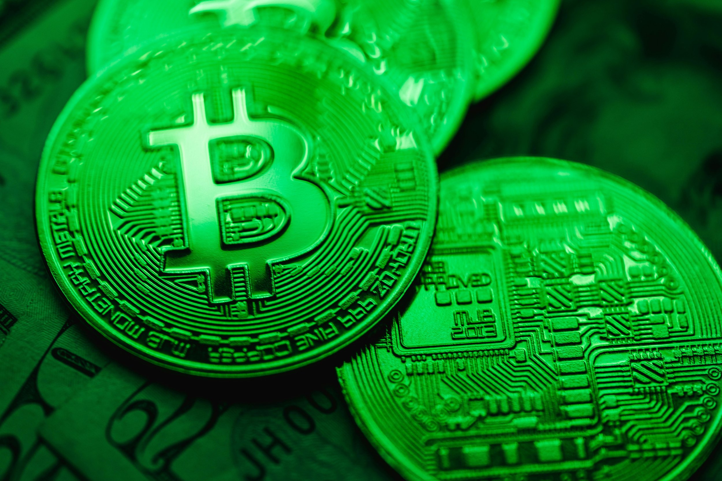 Stacks of physical bitcoins illuminated with green lighting, symbolizing eco-friendly blockchain technology and sustainable digital innovation.