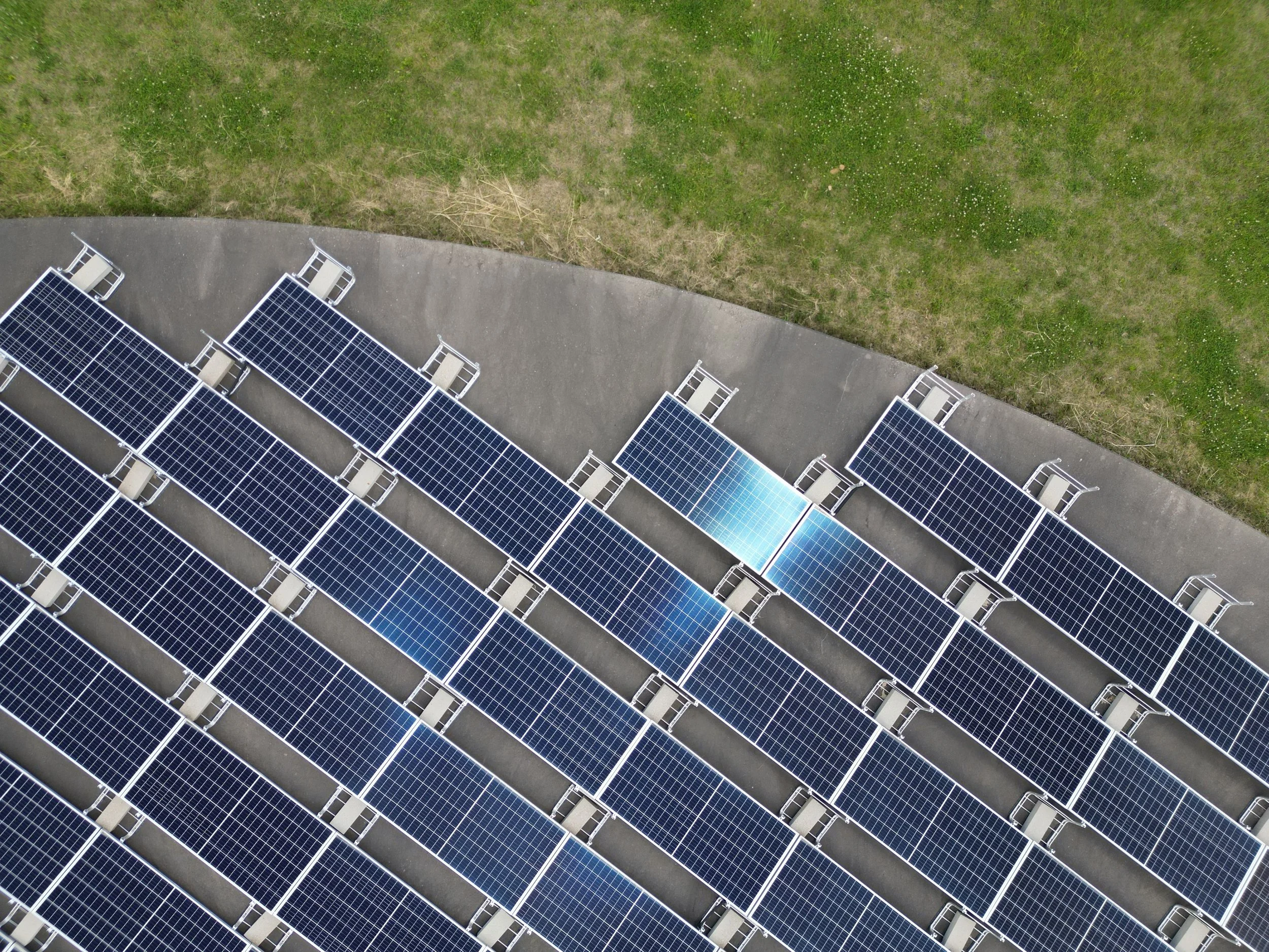 Top-down view of solar panels arranged across a green field, representing renewable energy generation and modern solar energy systems.