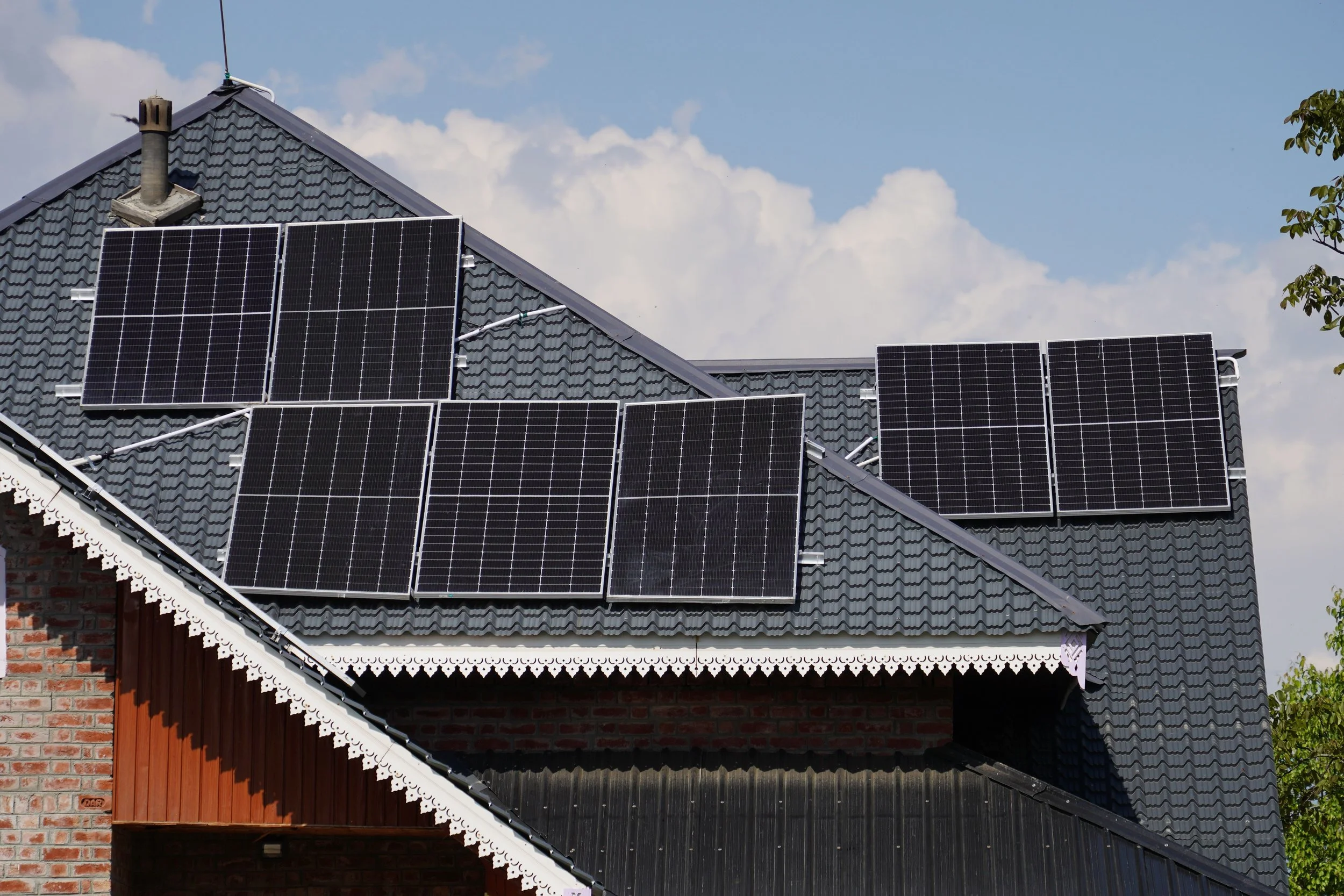 Rooftop solar panels installed on a house against a clear blue sky, representing renewable energy generation and modern solar energy storage solutions.