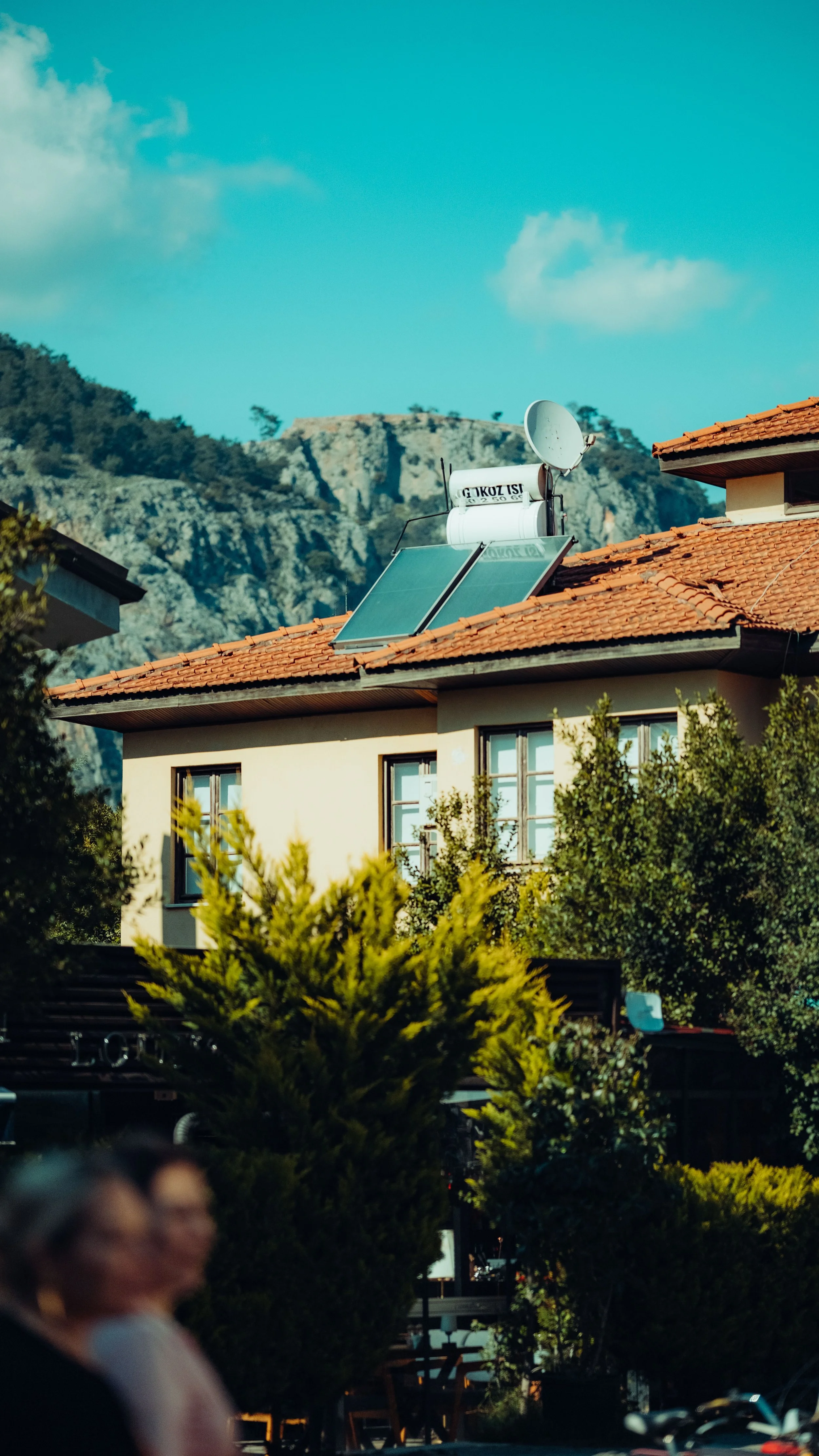 Urban house with rooftop solar panels and a mountain view in the background, representing solar irradiance and renewable energy generation in residential settings.