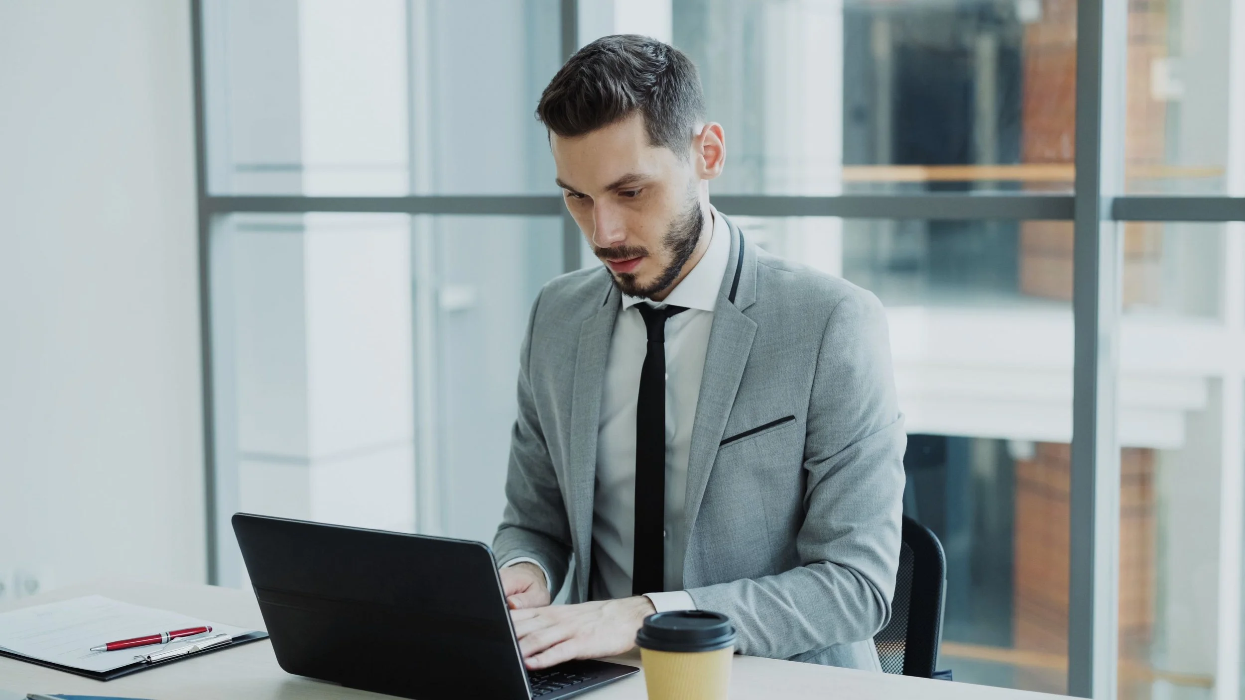 Businessman working on a laptop in a modern office, representing purposeful productivity, effective time management, and professional wellbeing.