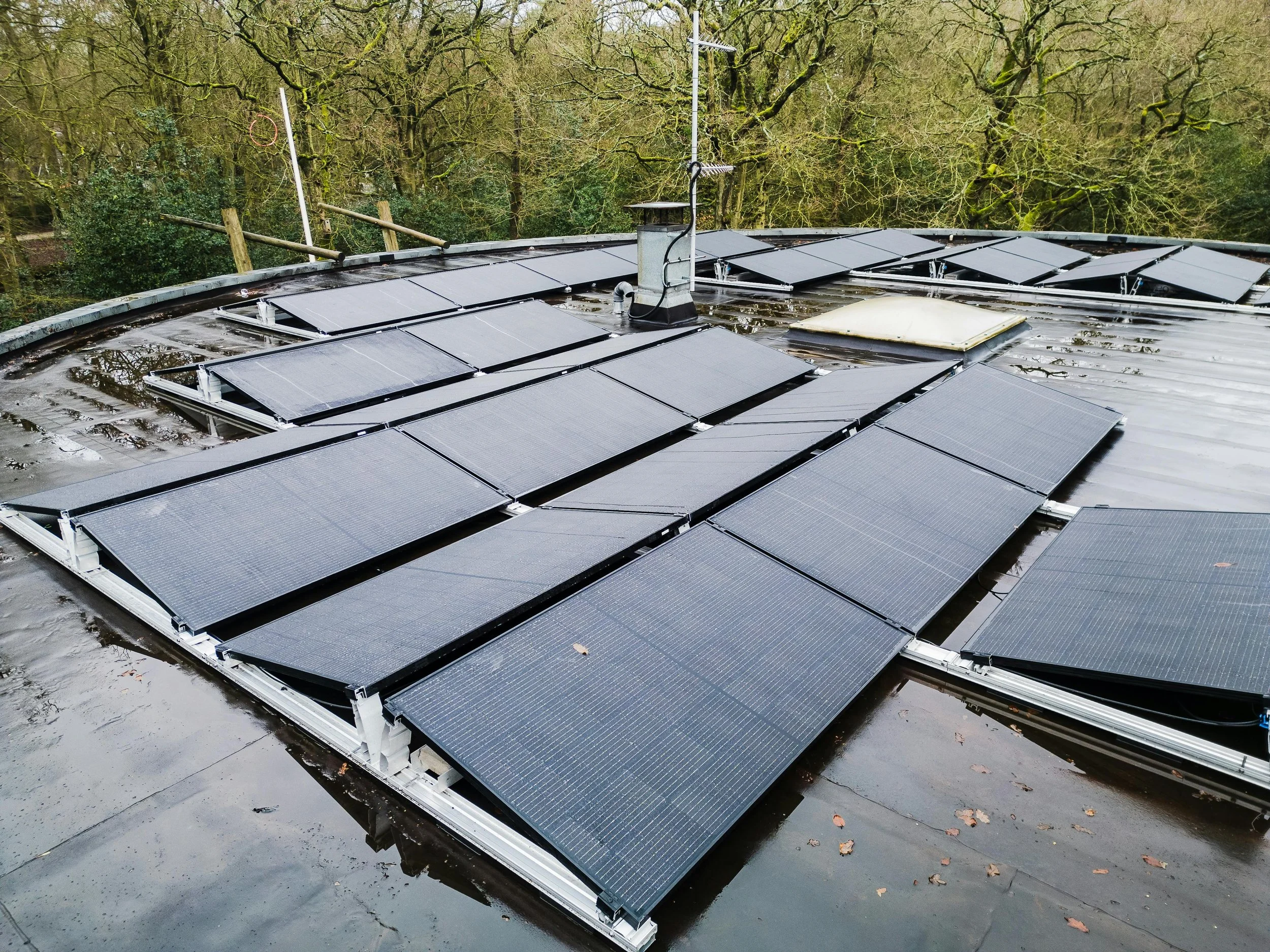 Solar panels installed on a rooftop surrounded by greenery, representing renewable energy efficiency and environmentally friendly living.