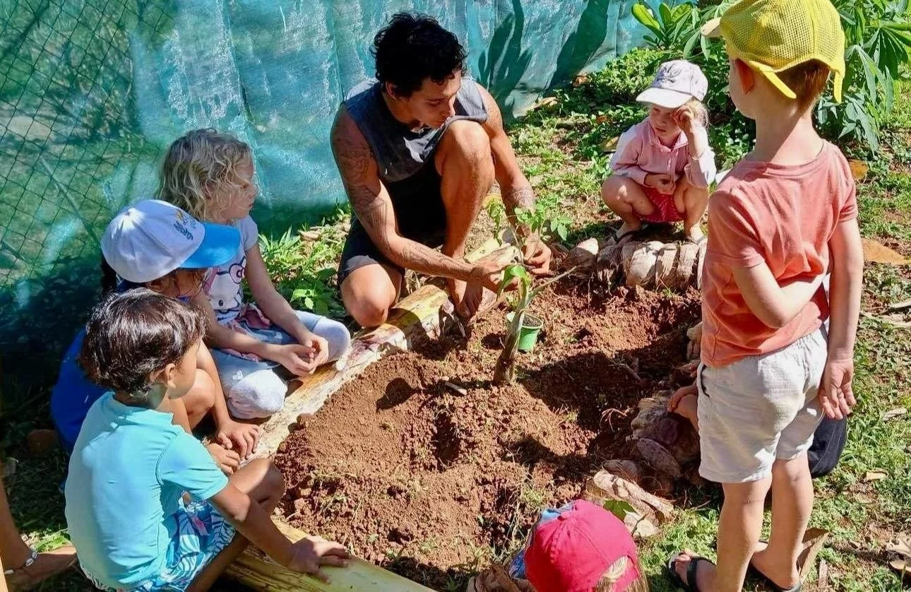 Enfants participant à un atelier de permaculture pour apprendre les principes du jardinage écologique pendant les stages vacances à l’École Fare Anuanua