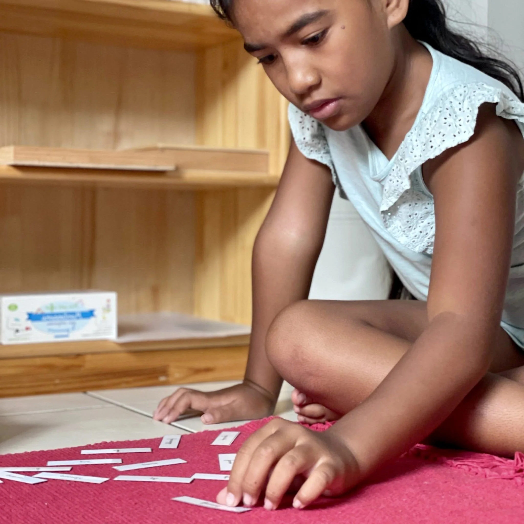 Enfant manipulant la série rose lors d'une activité Montessori à l’École Fare Anuanua à Moorea