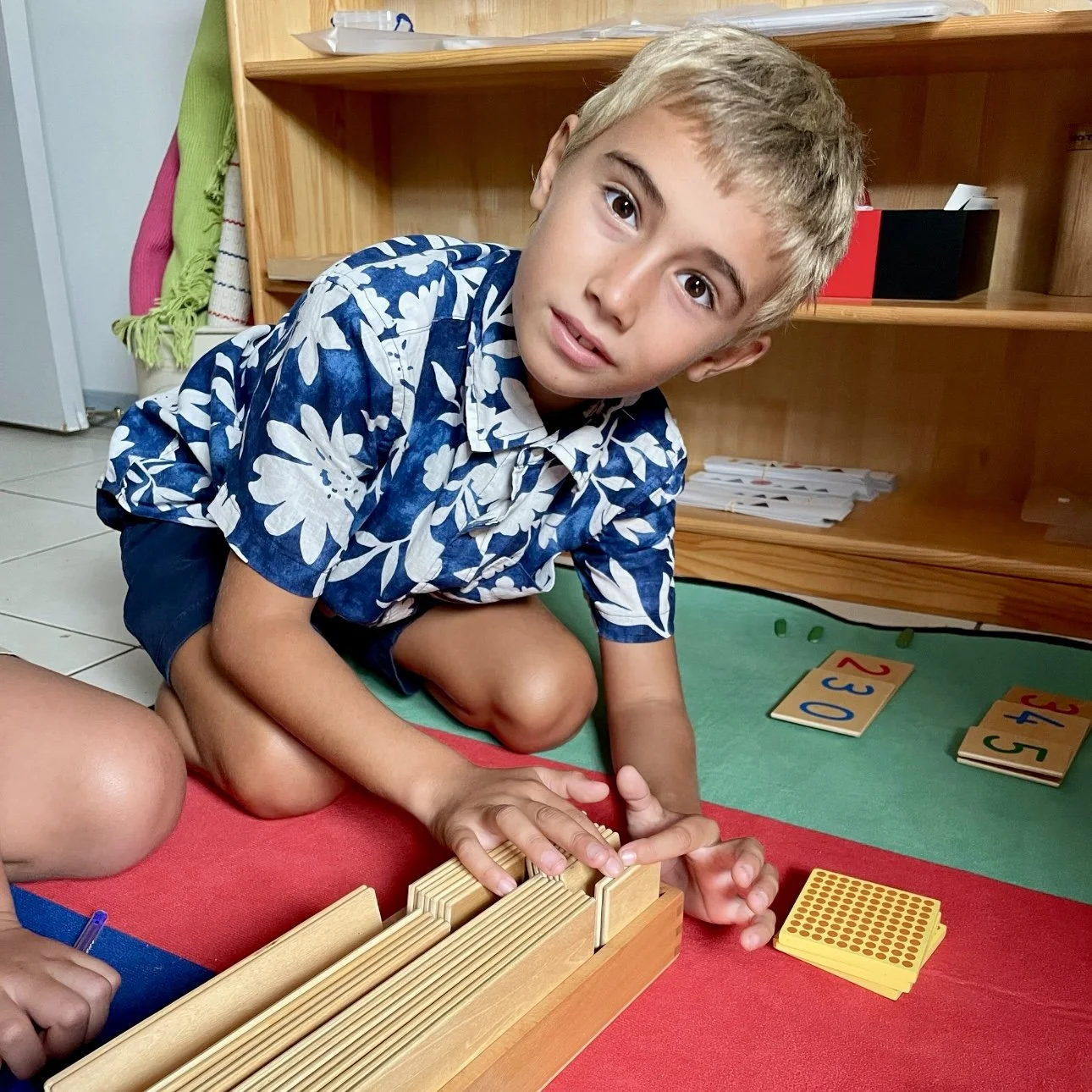 Enfant manipulant le matériel mathématique lors d'une activité Montessori à l’École Fare Anuanua à Moorea