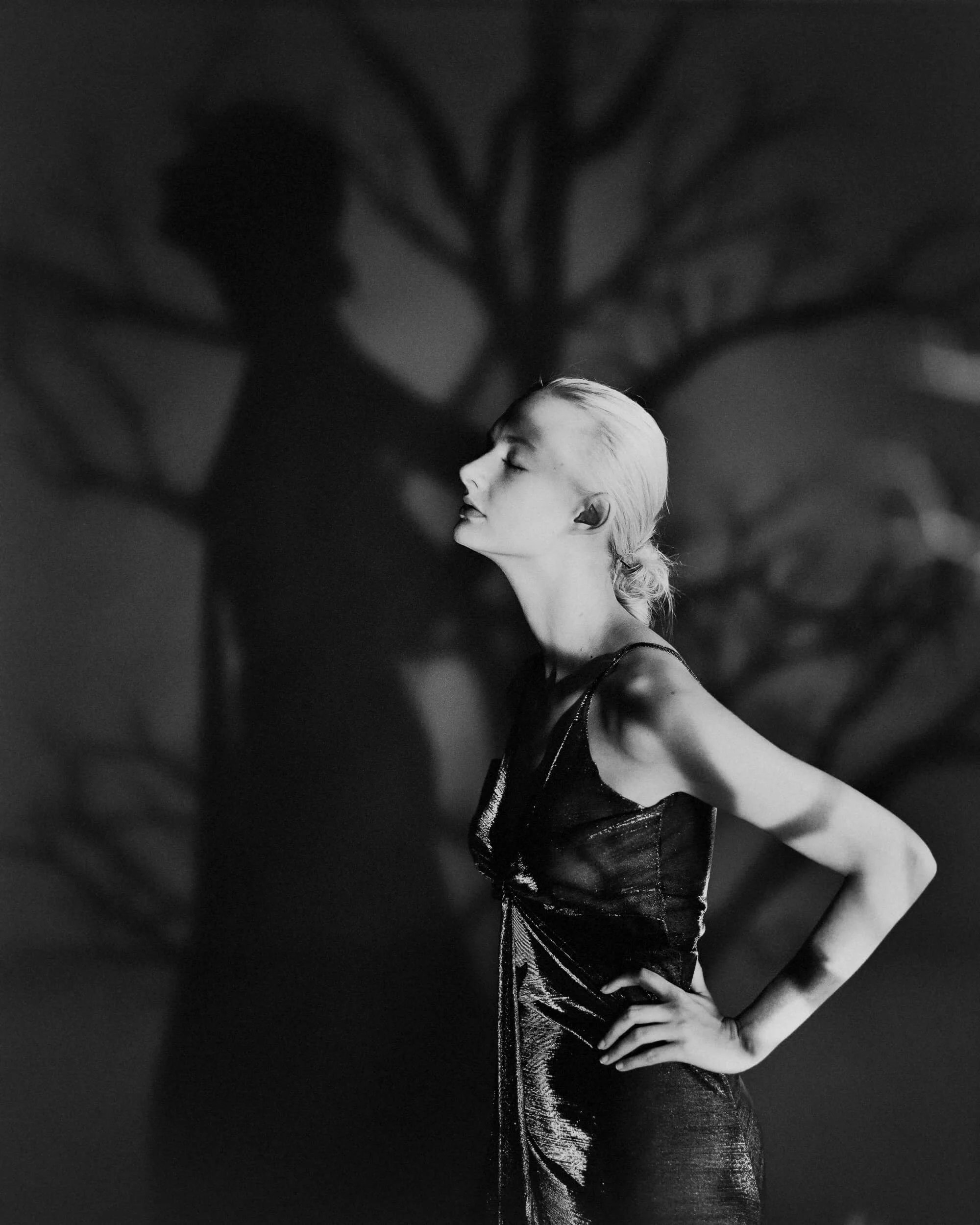 Parker J Pfister Fine Art Portrait of black and white photo of white woman with tree silhouette in background looking up and way with eyes closed.