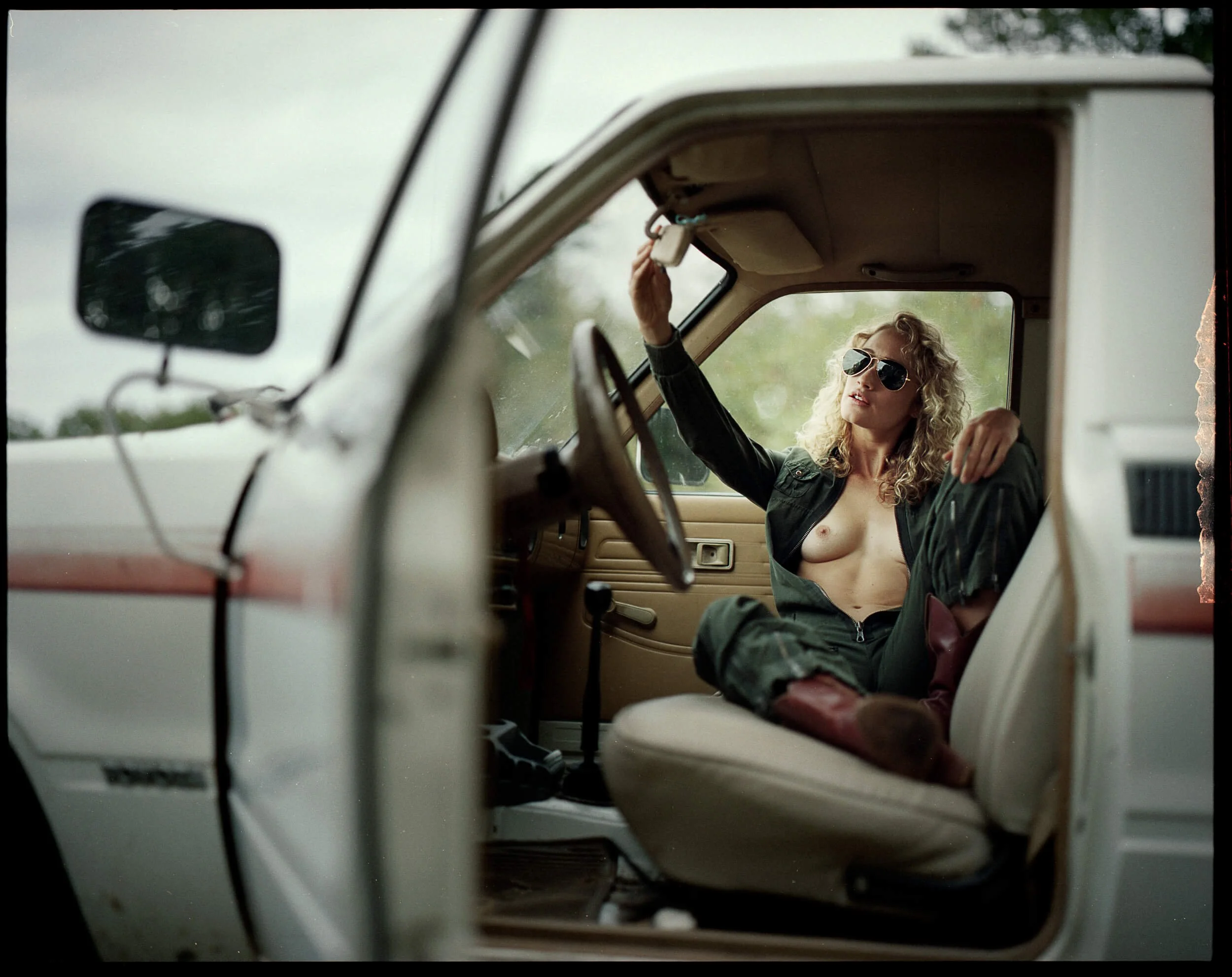 Parker J Pfister Fine Art Portrait looking through the open door of a vehicle of a white woman relaxing on the passenger seat.