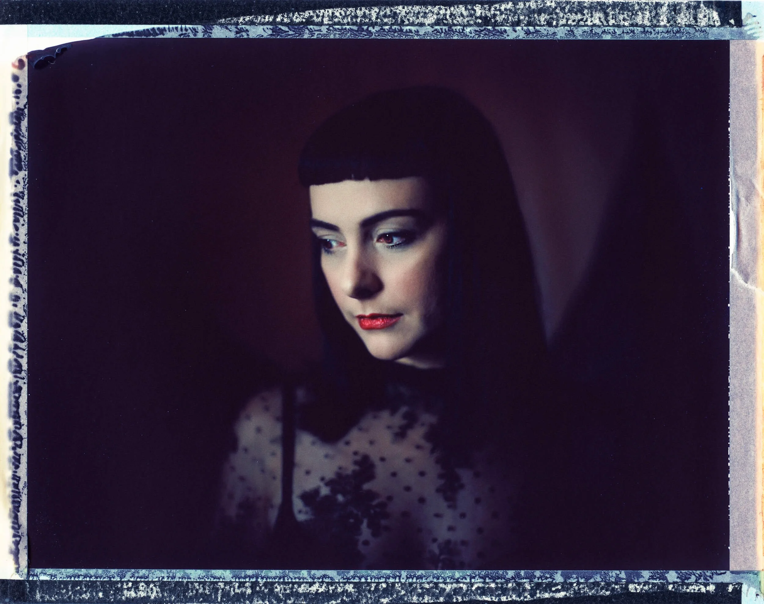Parker J Pfister Fine Art Portrait of a white woman with black hair and a black lace top looking down and away from the camera.