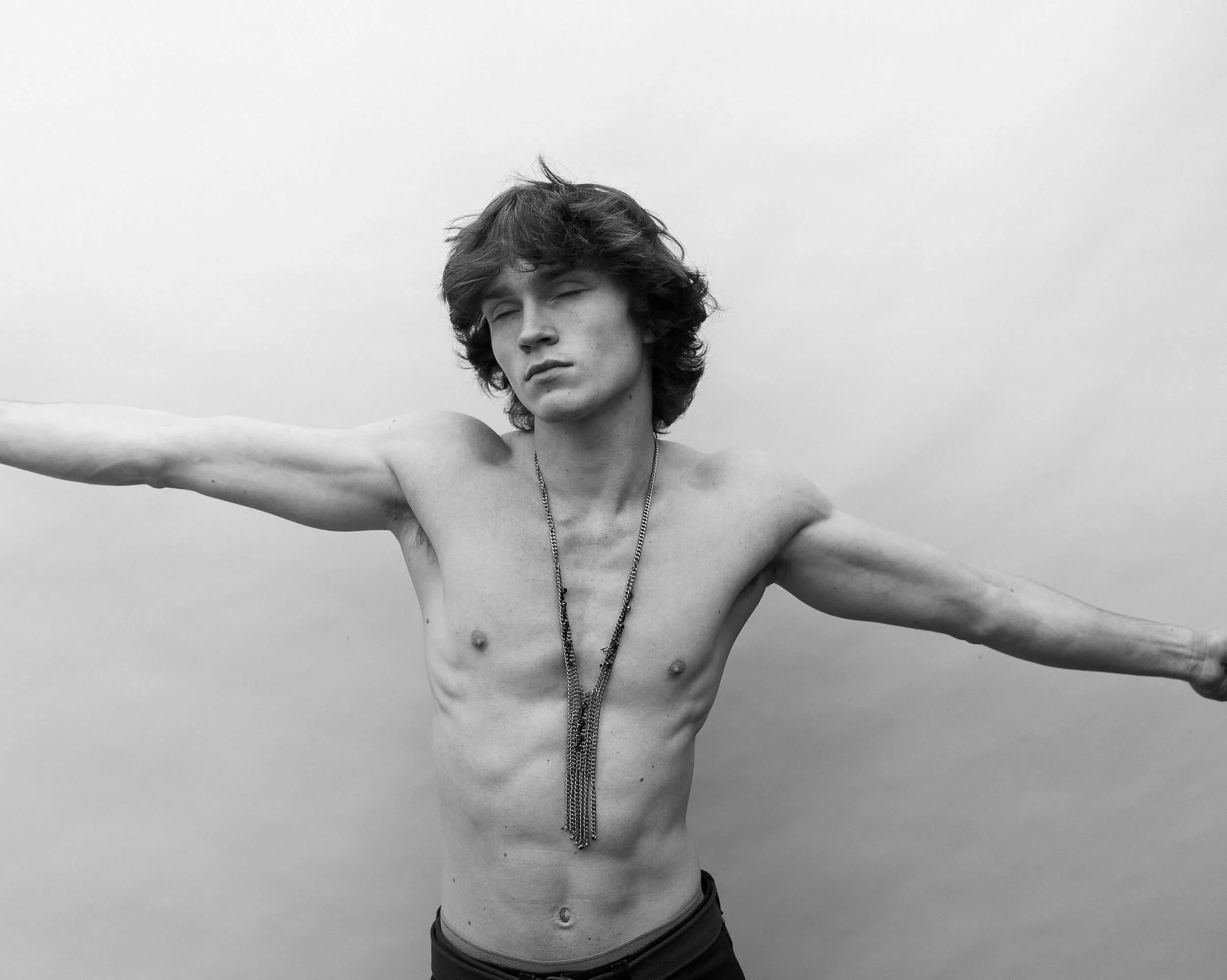 Parker J Pfister Fine Art Black and White Photography of a young white male without a shite hold his arms out with his eyes closed.