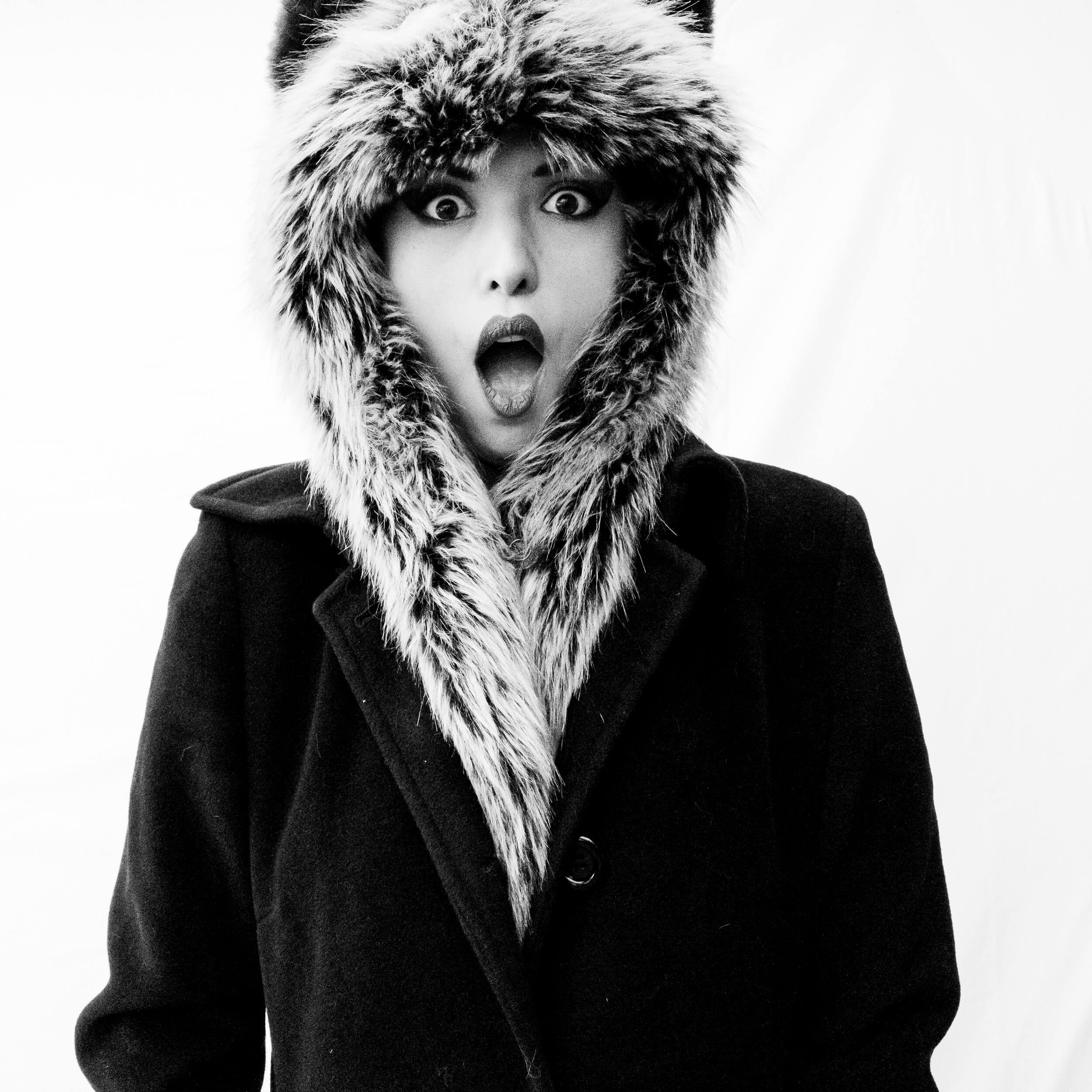 Parker J Pfister Fine Art Black and White Photography of a white woman looking surprised at the camera and wearing a fur hat and scarf.