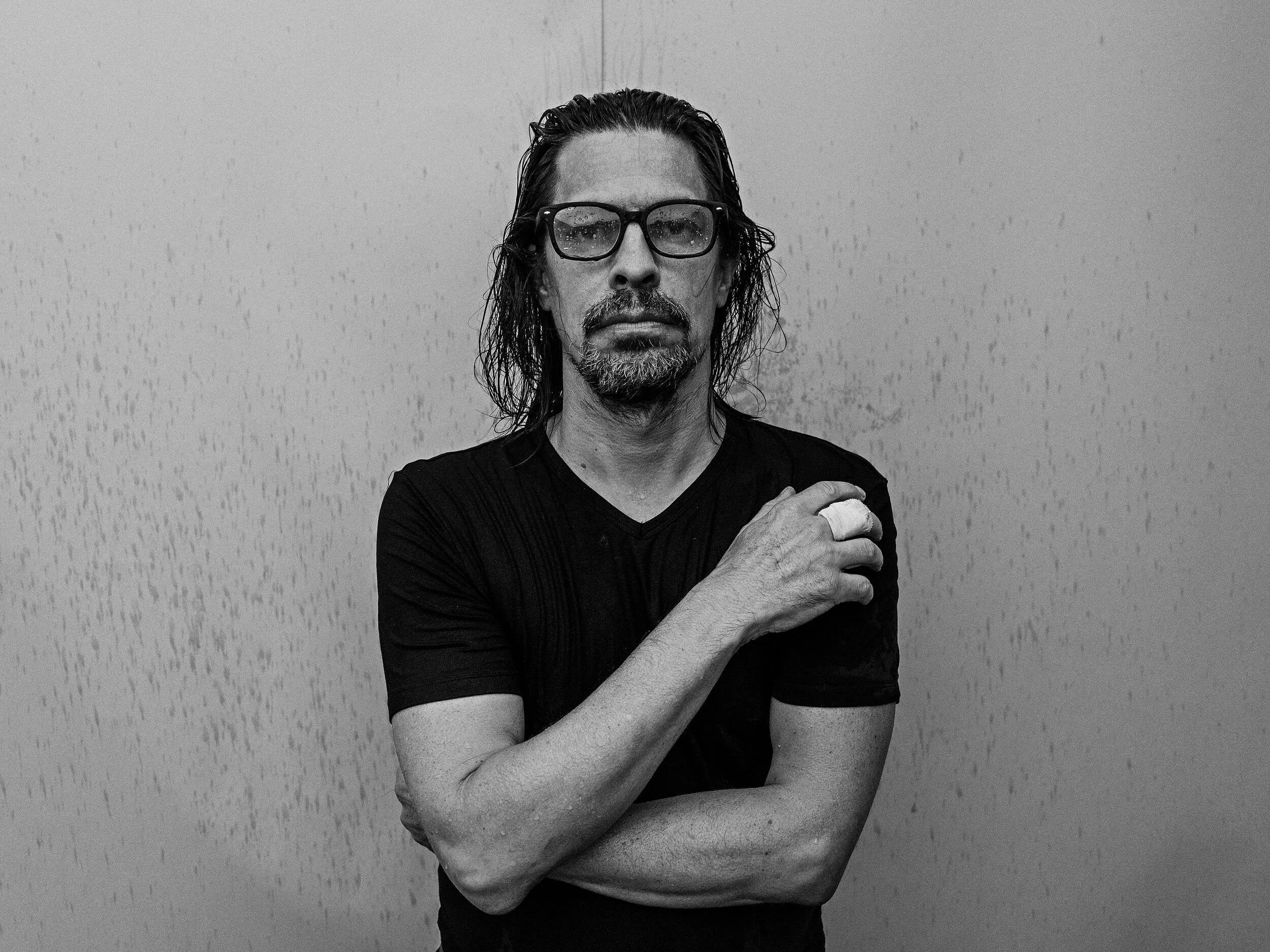 Parker J Pfister Fine Art Black and White Photography of a man with a goatee and glasses crossing his arms and looking stoic at the camera.