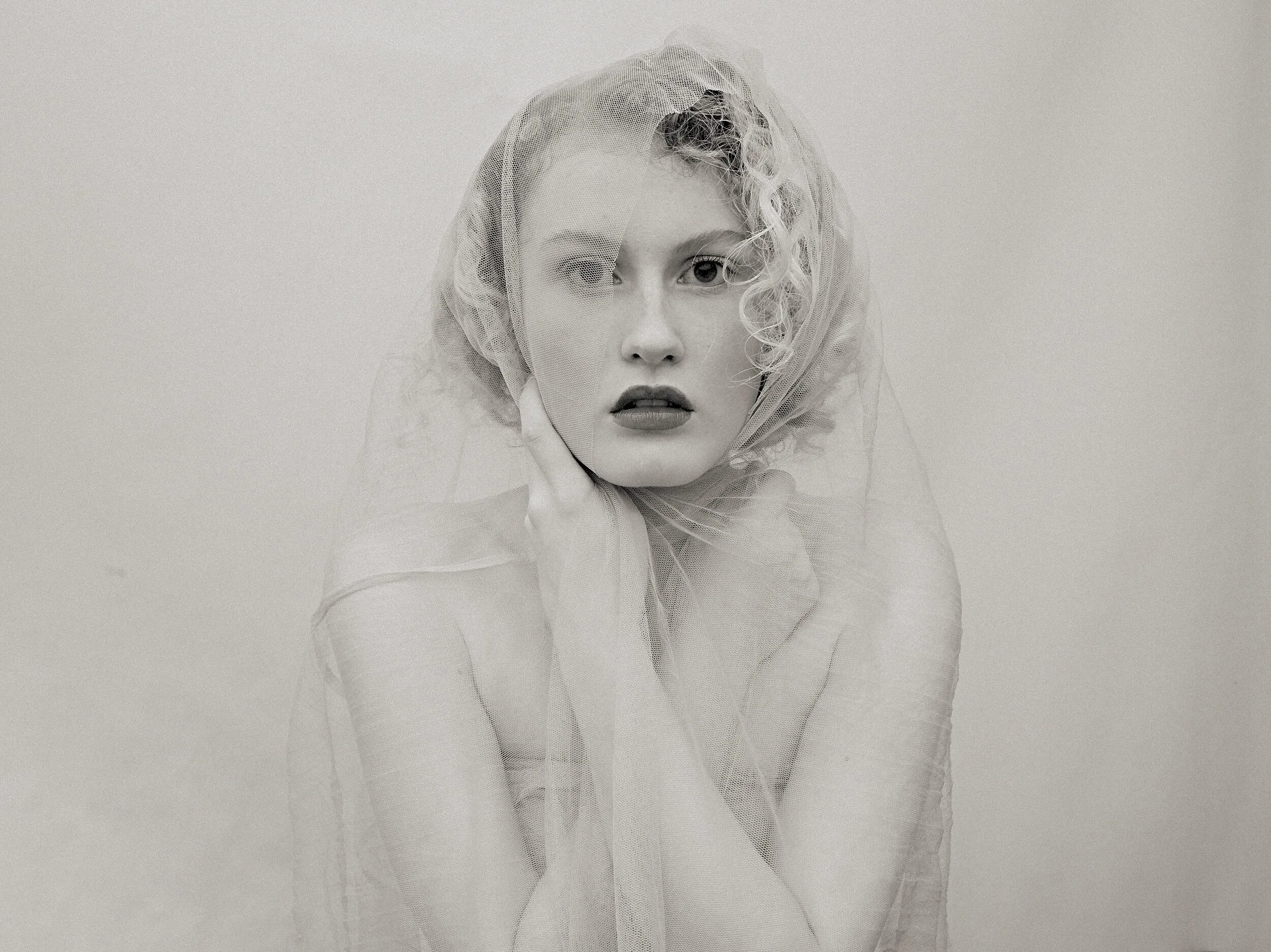 Parker J Pfister Fine Art Black and White Photography of a white woman covered in a sheer veil looking at the camera.