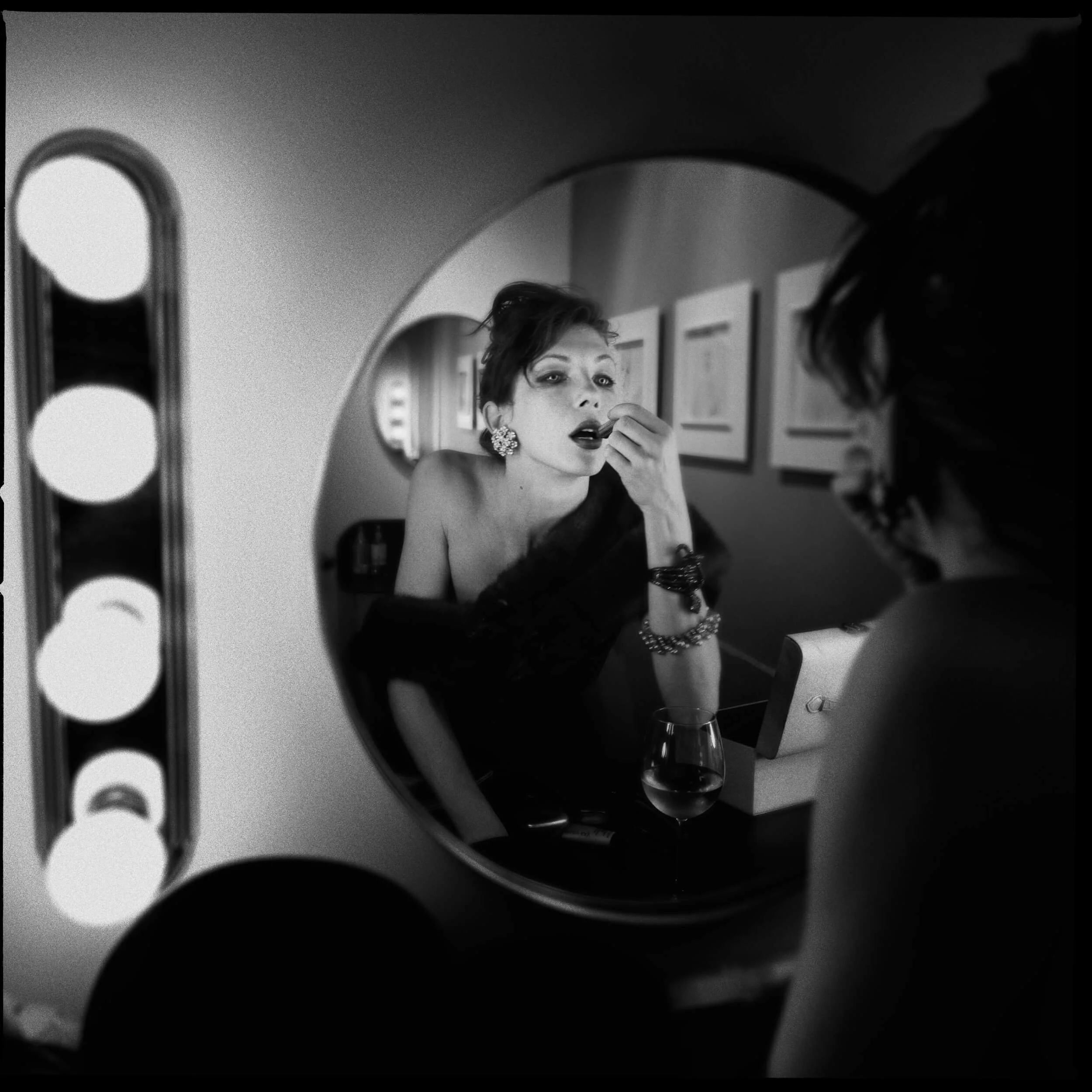 Parker J Pfister Fine Art Black and White Photography of a woman looking in a mirror and applying lipstick.