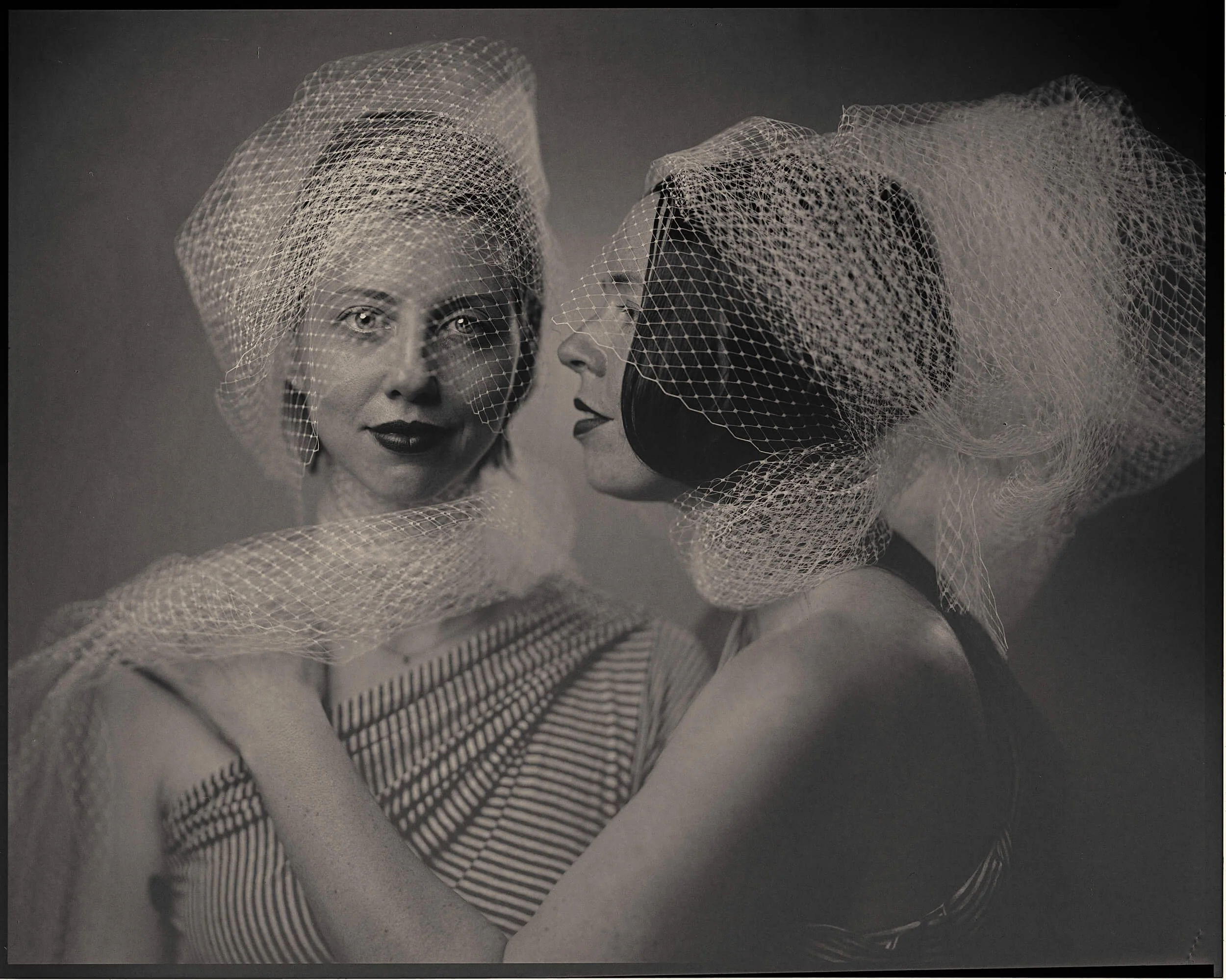 Parker J Pfister Fine Art Black and White Photography of two woman with tulle covering their heads whispering to each other.