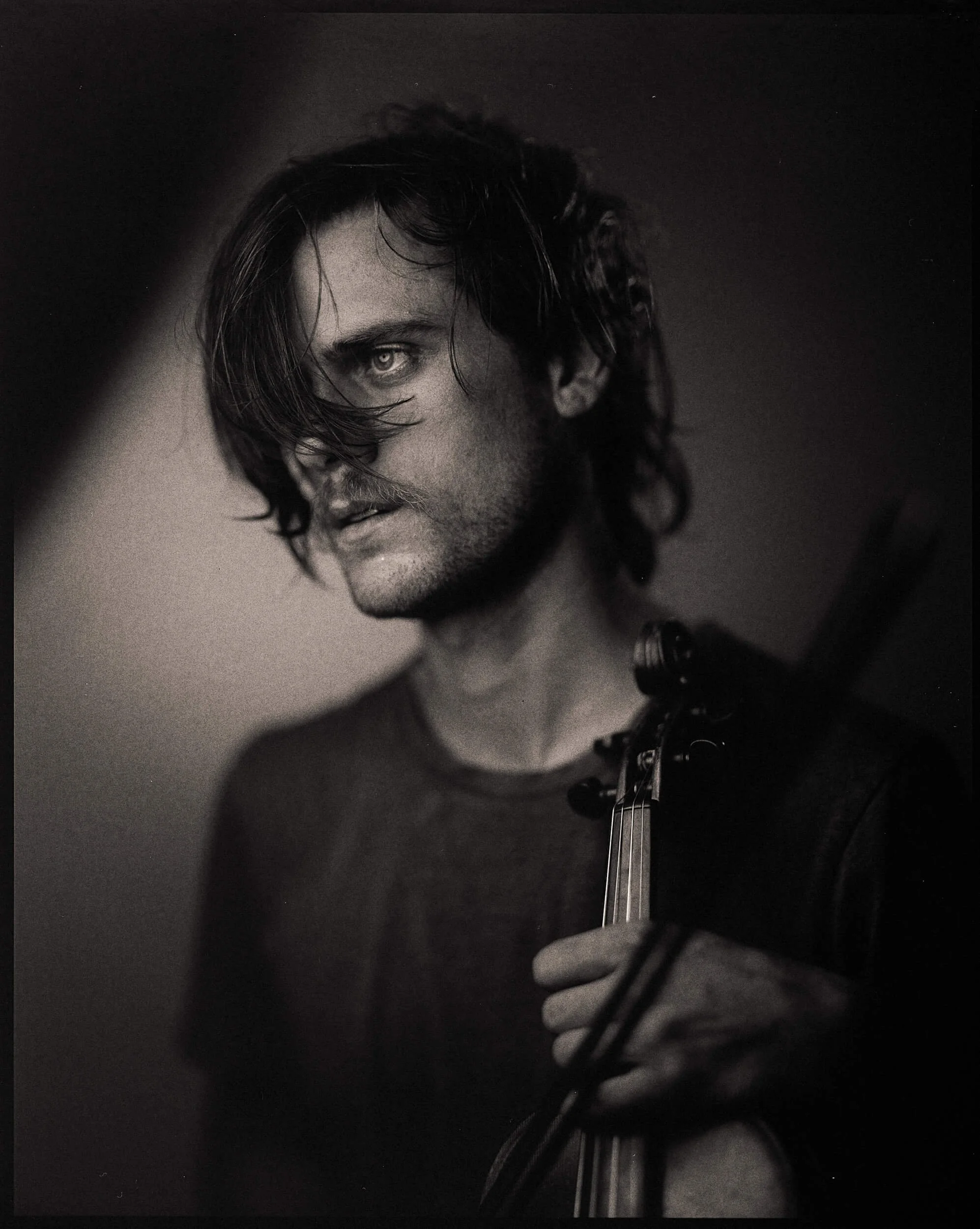 Parker J Pfister Fine Art Black and White Photography of a white man looking away from the camera and holding a violin and bow. 
