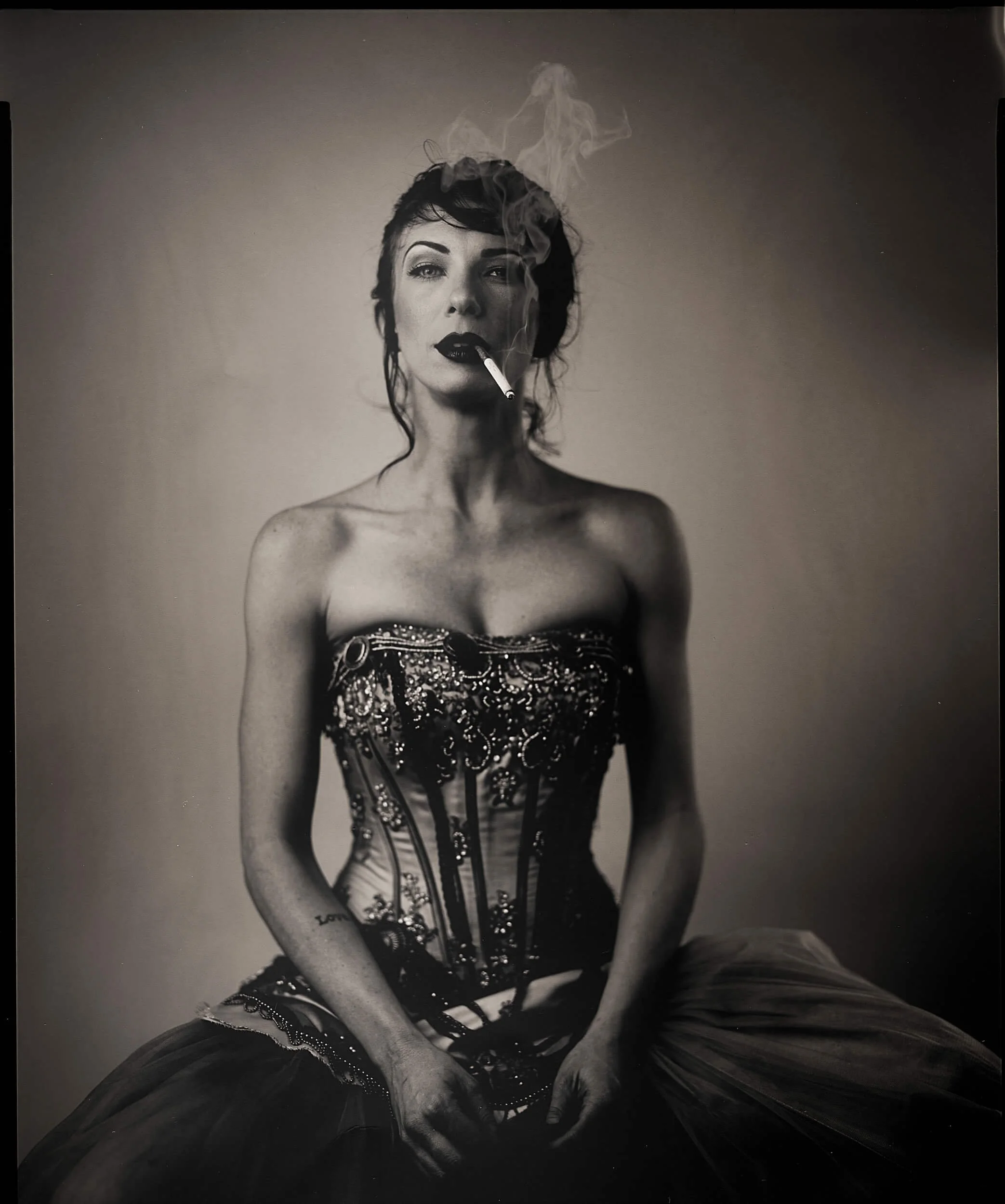 Parker J Pfister Fine Art Black and White Photography of a woman wearing a burlesque type dress with a cigarette in her mouth. 
