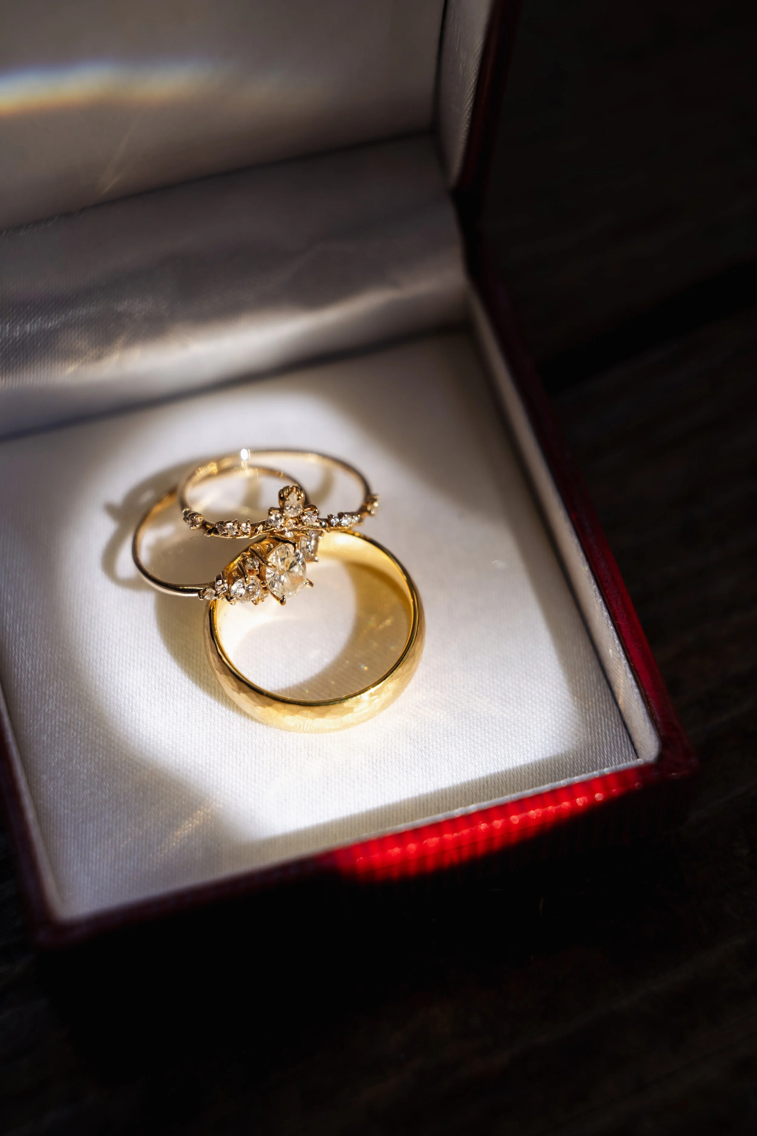 A jewelry box with two gold rings and a diamond ring inside.