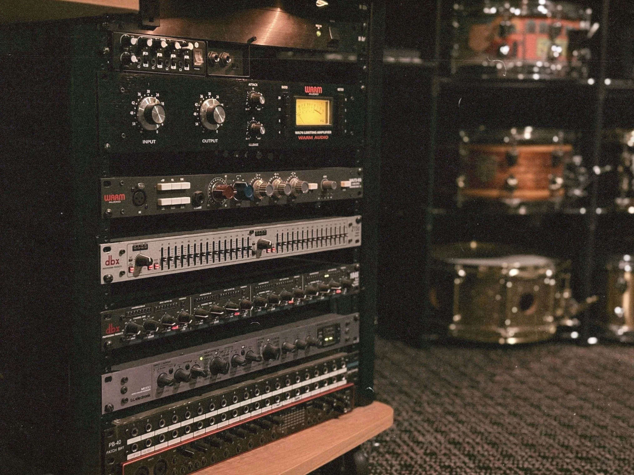 A collection of audio equipment and sound mixing devices on a rack against a dark background.