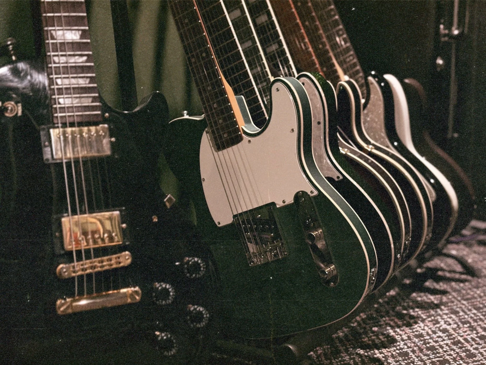 Multiple electric guitars hanging on a rack in a music store.