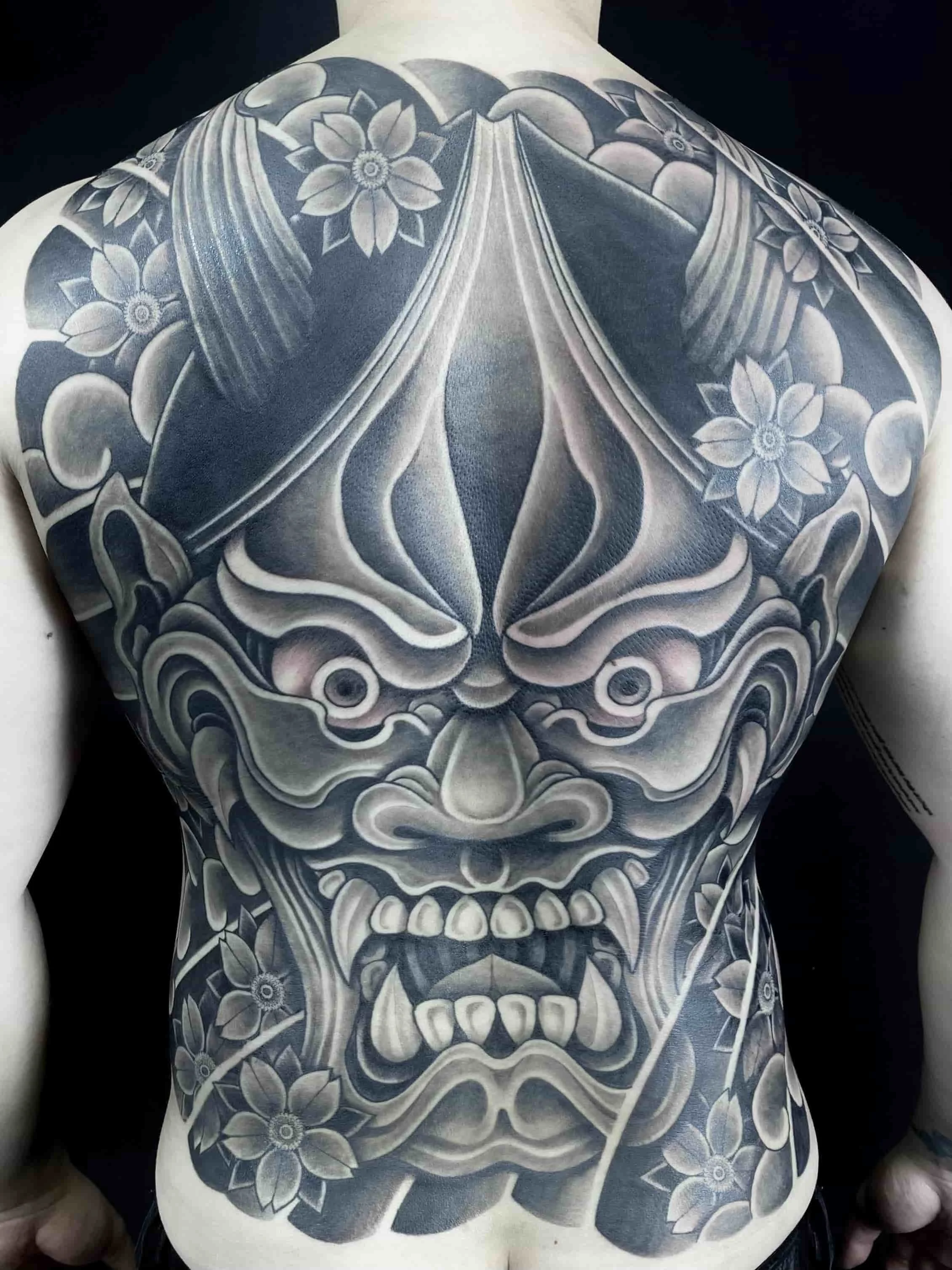 Large Japanese backpiece tattoo.  Black and grey hannya mask with sakura (cherry blossoms).  Tattooed by Cohen Floch in Victoria BC, Vancouver Island.