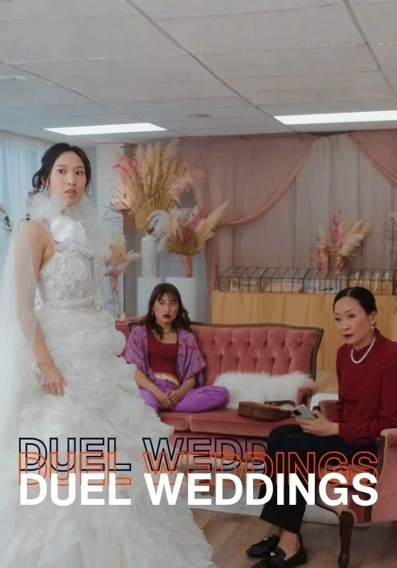 Three women in a room decorated for a wedding. One woman is in a wedding dress, another is sitting on a pink sofa, and the third is sitting on an armchair reading a book. The room has pink and beige curtains with floral decorations. The text overlay says "DUEL WEDDINGS."