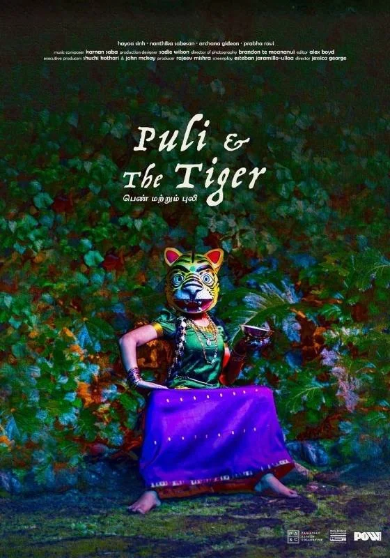 Poster for short film " Puli and the Tiger". A person wearing a tiger mask and traditional clothing, sitting on the ground surrounded by green foliage, holding a cup in one hand.