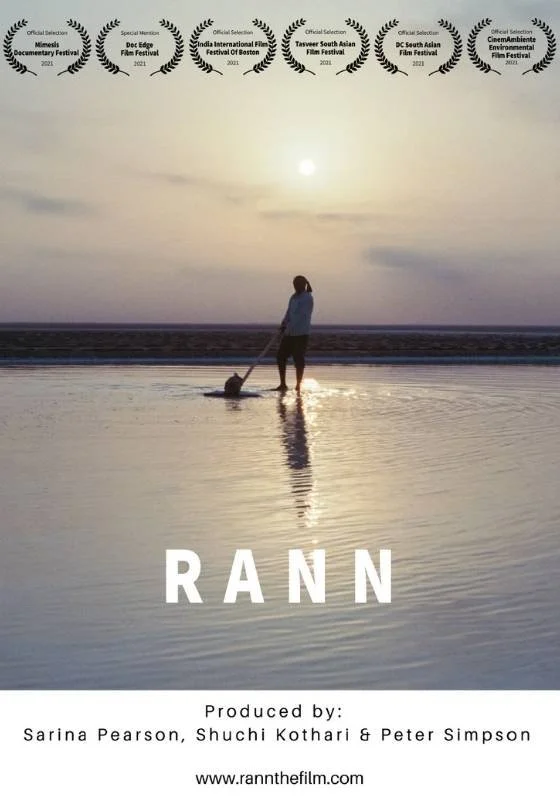 Poster for documentary short 'Rann'. A person standing on a beach during sunset with laurels at the top and the title RANN at the bottom.