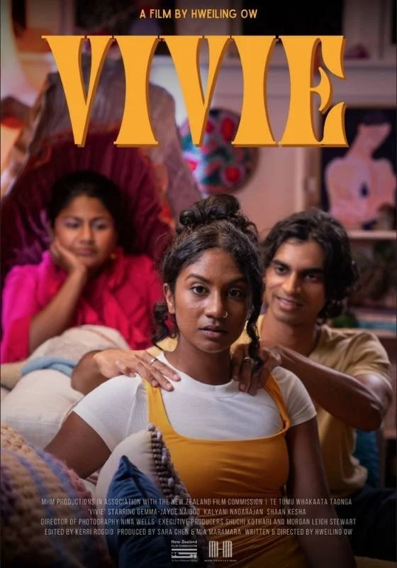 Poster for the film 'VIVE' with three young people in a cozy indoor setting. The girl in the foreground has dark curly hair and wears a white shirt with an orange tank top. Behind her, a boy with shoulder-length dark hair smiles, and a girl in the background, reclining on a sofa, rests her chin on her hand, wearing a pink shirt.