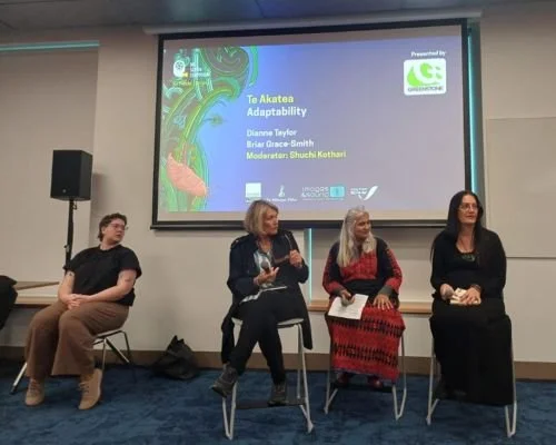 Shuchi Kothari and three other women sitting on chairs in front of a large screen at a panel discussion at BSS 2026, with a title slide about 'Te Akatoa Adaptability' and names of speakers and moderators. The room has a blue carpet.
