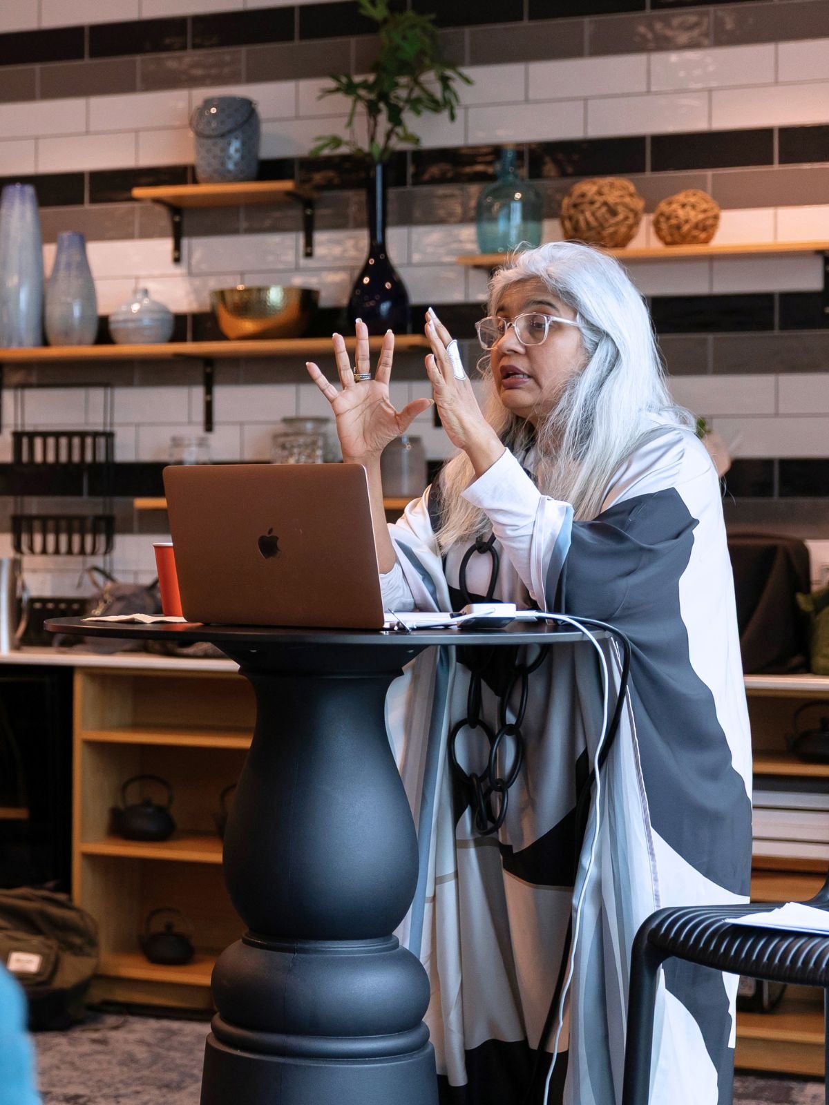 Shuchi Kothari presents at a podium with an Apple laptop on front of her