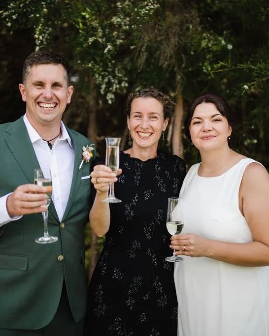 Three smiling people; the groom, the celebrant, the bride