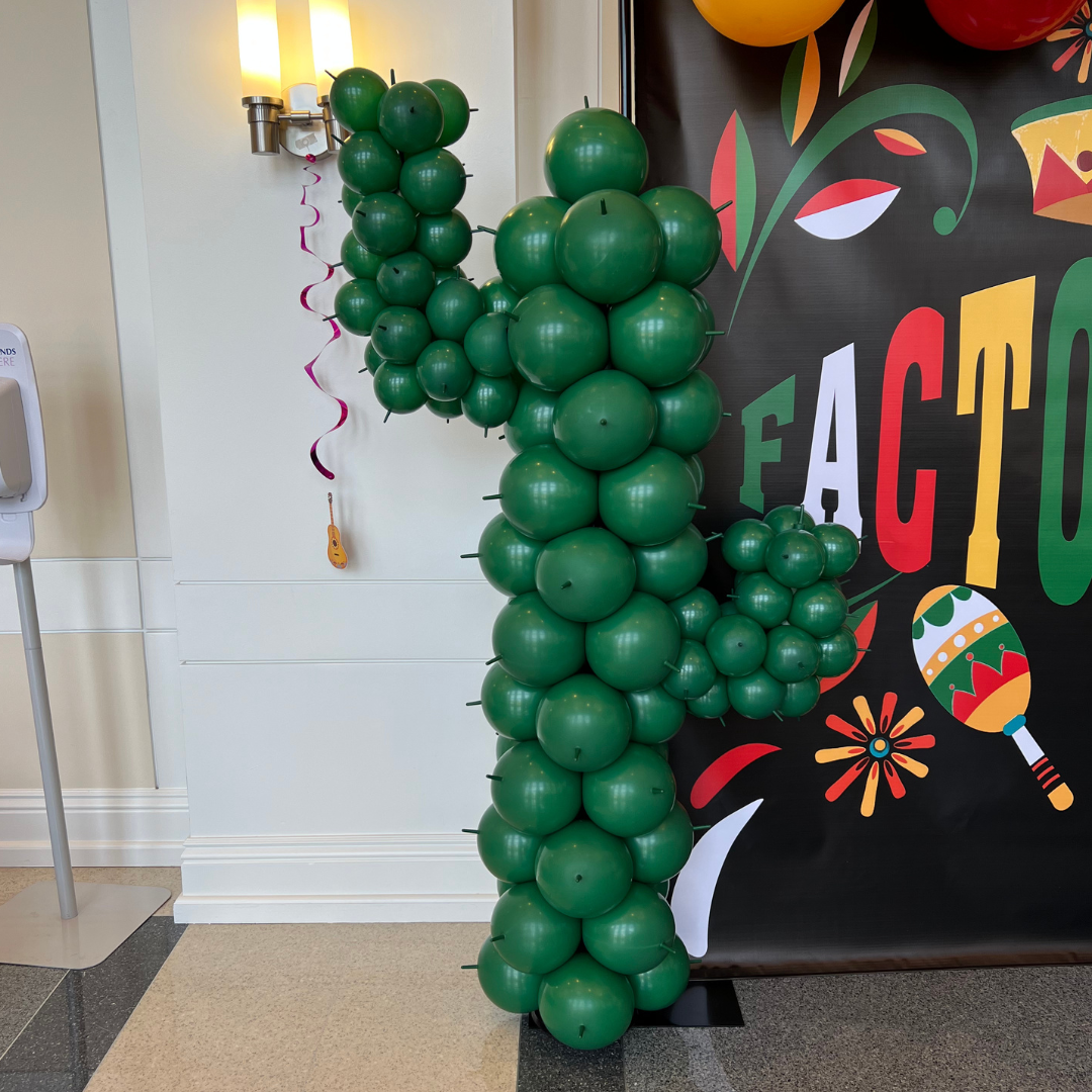 Decorative display of green balloons arranged in the shape of the number 1, with a festive backdrop and balloons in the background.